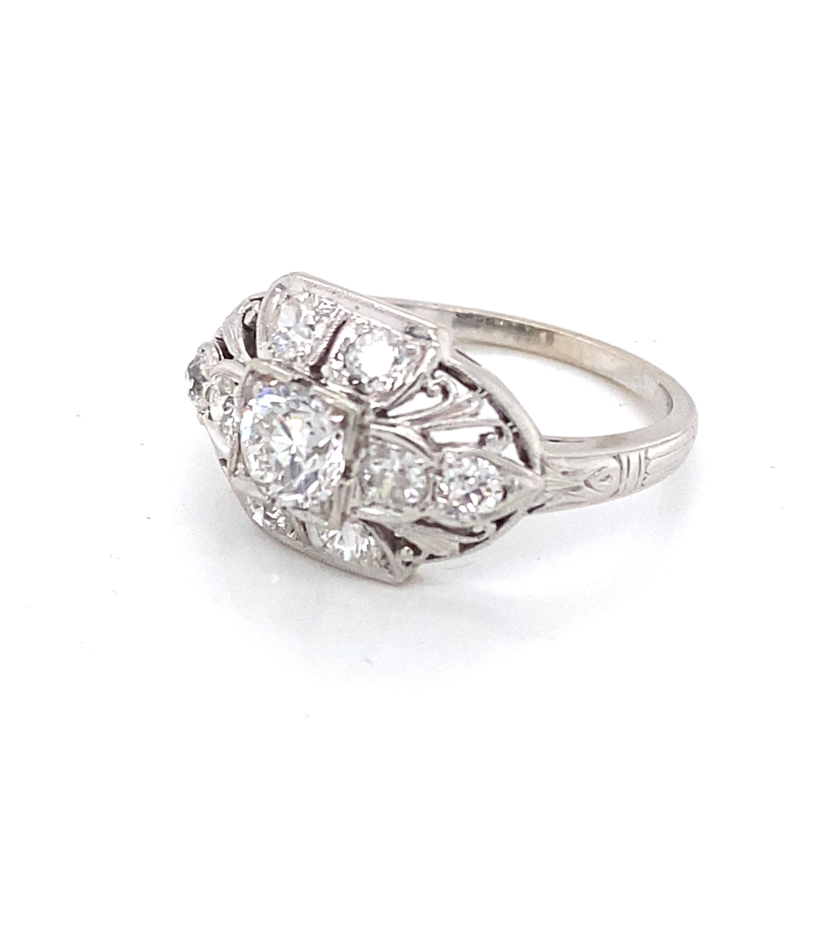 A bright and shining 5.4mm old European-cut diamond crowns a sparkling slightly domed Art Deco ring ornamented with eight old European-cut accent diamonds, intricately accentuated by delicate hand piercing and milgraining. The diamonds weigh