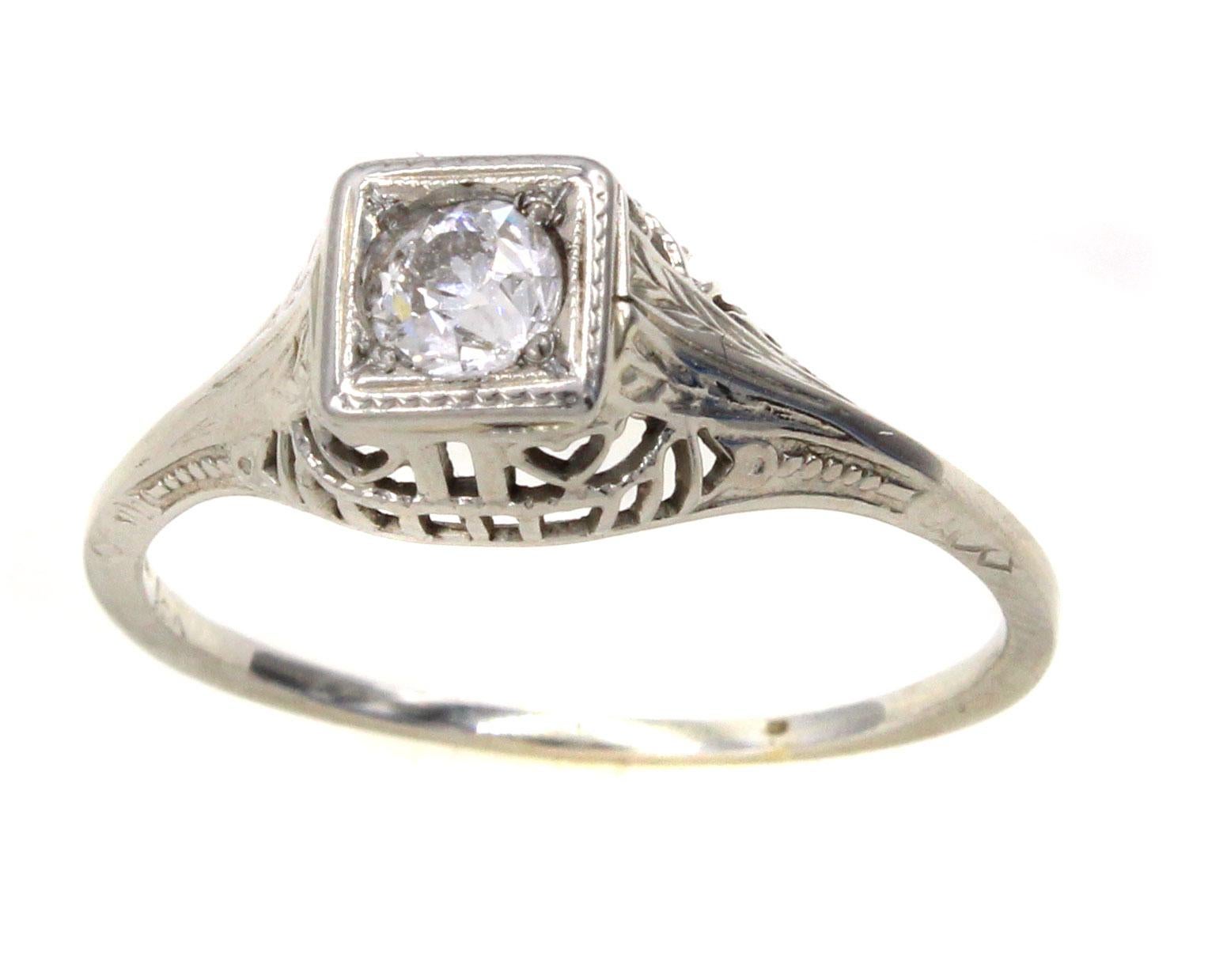 This well handcrafted Art Deco 18 Karat white gold engagement ring is centrally set with a bright white Old European cut diamond measured to weigh approximately 0.30 carats. The gallery is has beautiful a-jour work and fine hand engraving. A