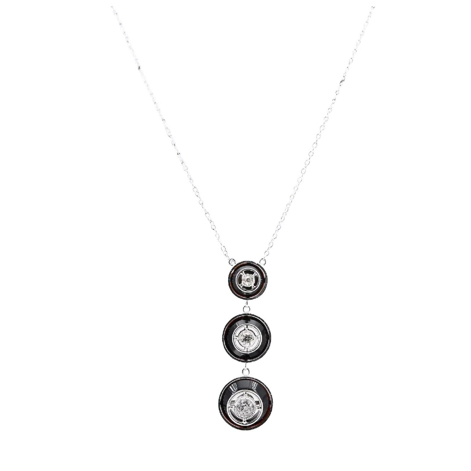 An Art Deco period diamond and onyx journey style target necklace in platinum.

Centered by three graduated diamonds set in miligrain beaded platinum bezels against a backdrop of polished black onyx.

The diamonds weighing 0.05, 0.10 and 0.25 carats