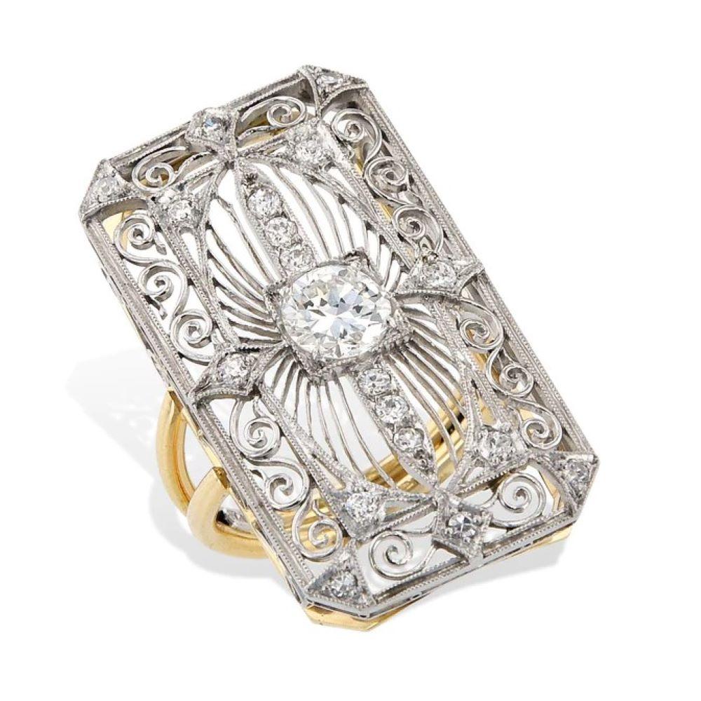 This exquisite Art Deco platinum and 18 karat yellow gold ring features a stunning 0.78 carat transitional diamond at its center surrounded by 18 Old European Cut diamonds totaling 0.48ct. The ring has been expertly crafted by repurposing a vintage