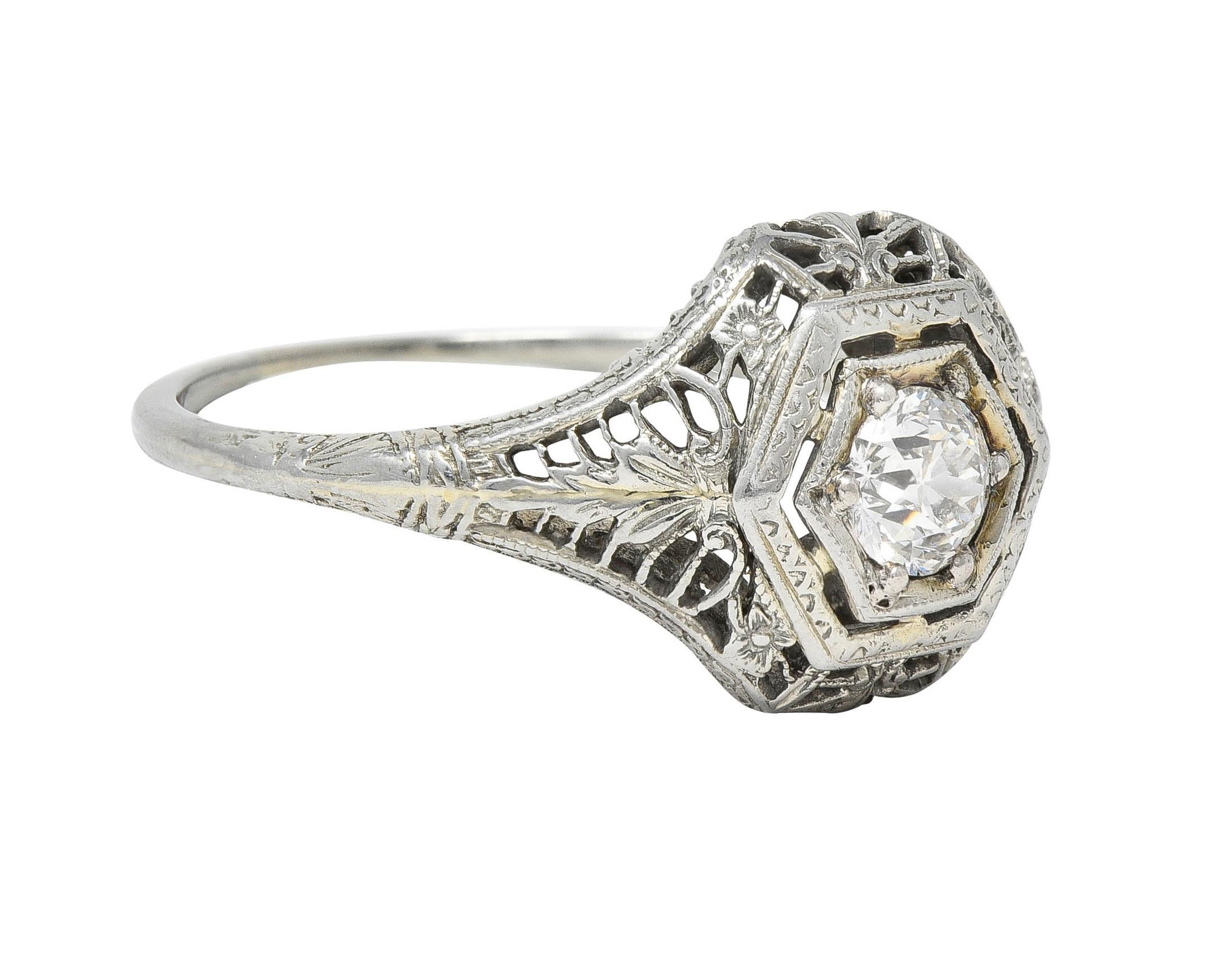 Centering an old European cut diamond weighing approximately 0.35 carat - G color with VS2 clarity
Bead set in a hexagonal form head with a hexagonal shaped bombé surround 
Pierced with orange blossom motif profile and foliate motif