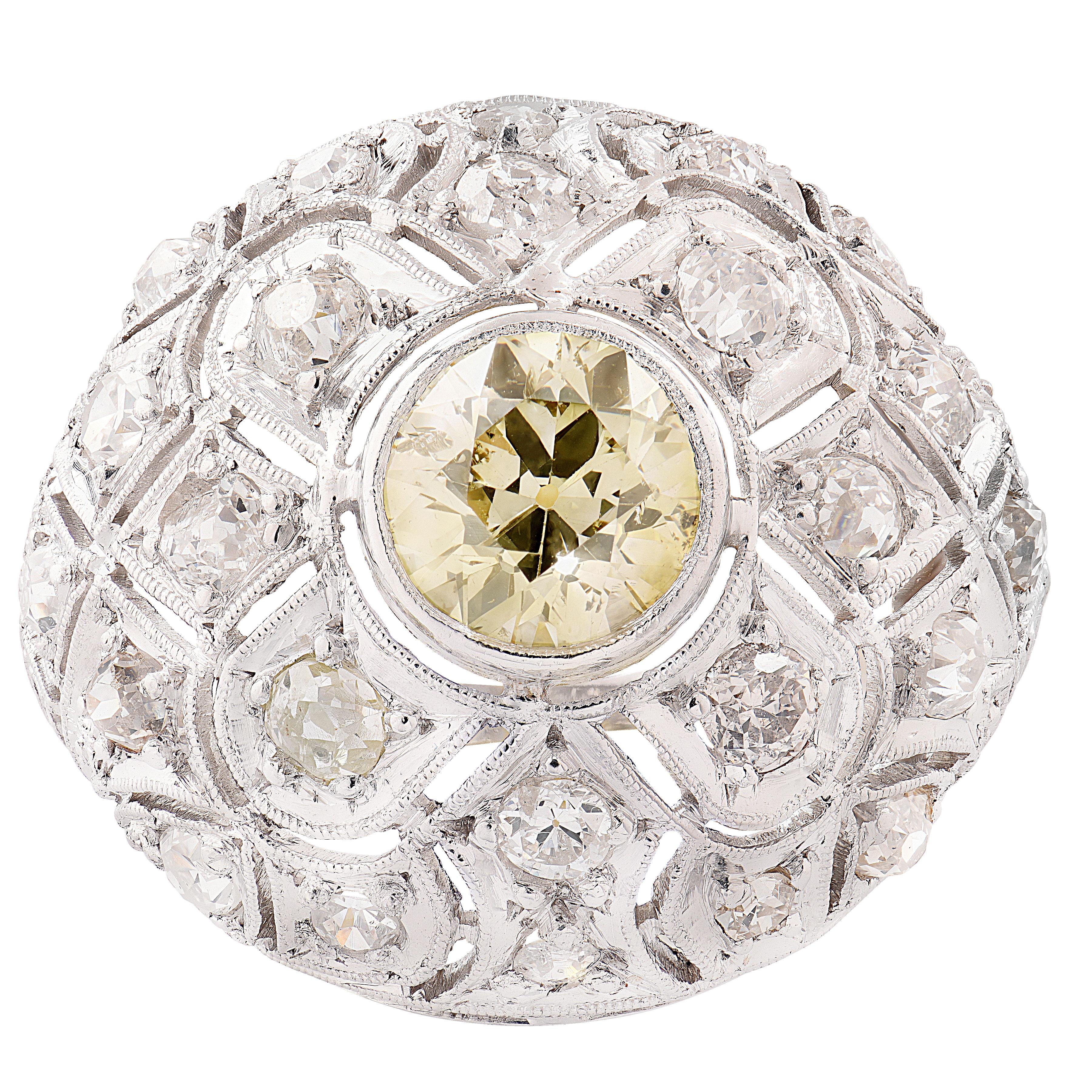 Elegamment réalisée vers 1920, cette bague bombe enchanteresse est composée de platine et d'or blanc 18k. En son centre repose un captivant diamant jaune fantaisie de taille Old European de pureté SI, rayonnant de chaleur et de charme vintage. La