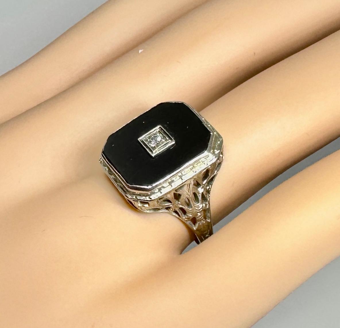 This is a very special Victorian, Art Deco Ring with a rectangular Black Onyx, a central Old Mine Cut Diamond, and beautiful 14 Karat White Gold work around the stunning gallery and extending down the ring shank.  The magnificent antique ring has a