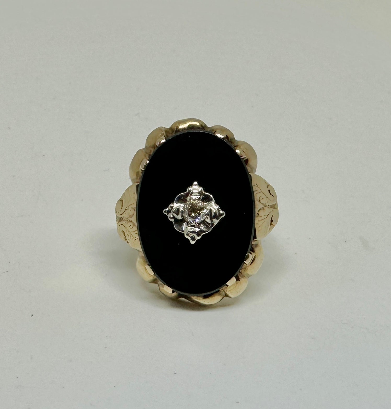 This is a very special antique Victorian to Art Deco ring with an oval shape panel of Black Onyx with a central Old Mine Cut Diamond set in 14 Karat Gold.  The stunning antique ring has a beautiful Black Onyx oval shaped gem.  The Onyx is set in a