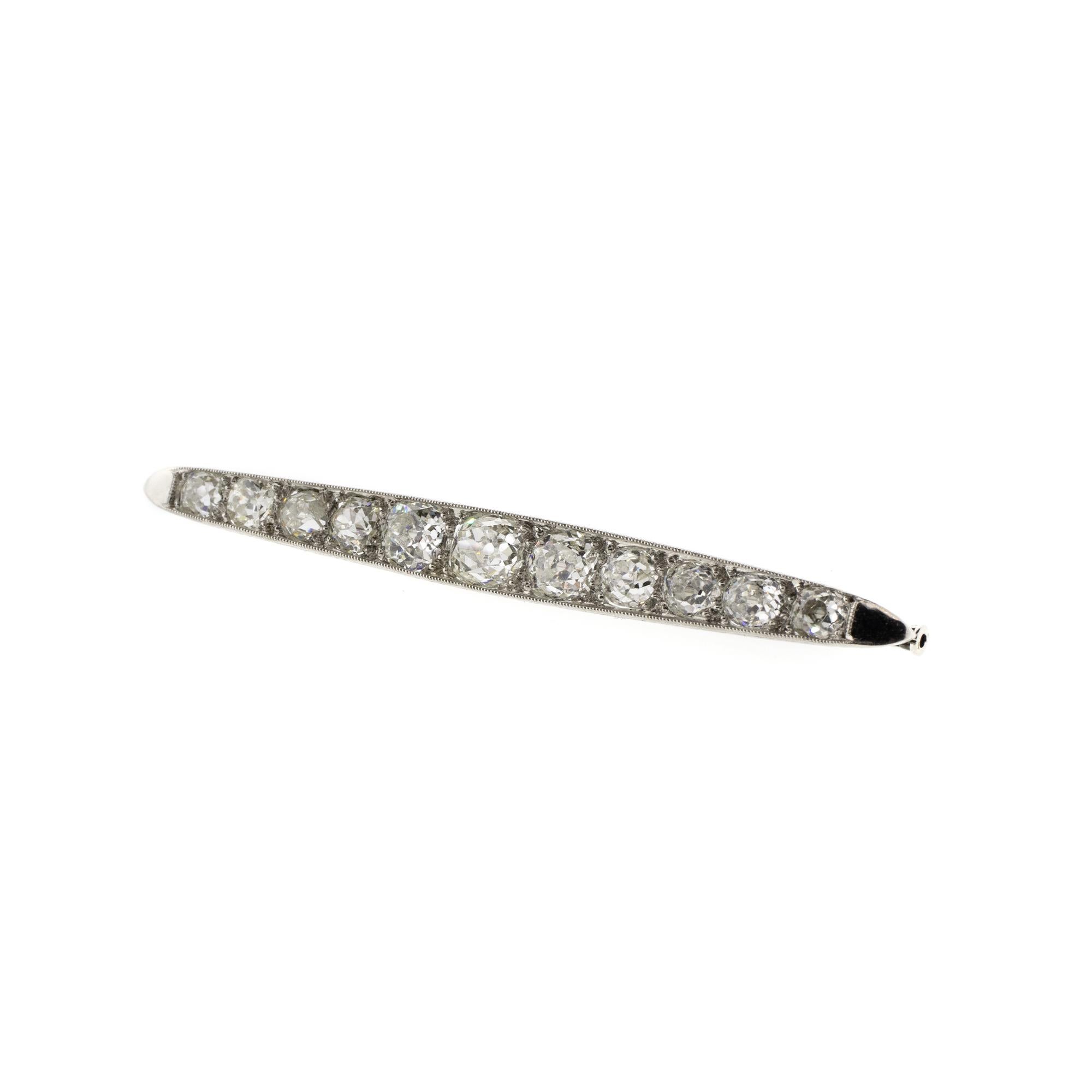 An antique original Art Deco brooch with a classic look and elegant details. Eleven graduated diamonds with a total carat weight of approximately 4.26ctw shine bright in gleaming platinum, with delicate scrollwork along the sides. The color of the