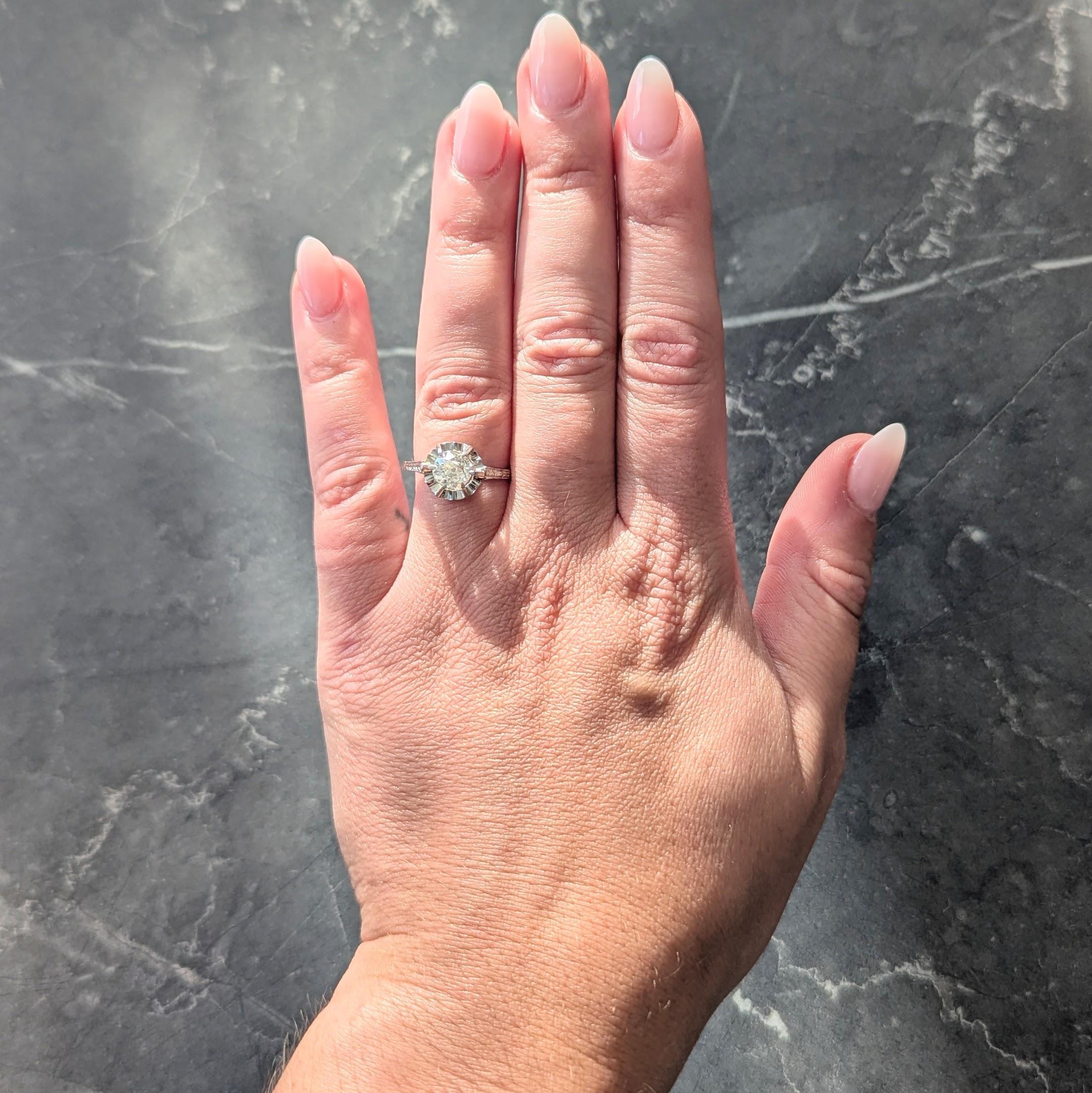 In der Mitte ein Diamant im alten Minenschliff mit einem Gesamtgewicht von etwa 0,90 Karat - Farbe K mit Reinheit VS2
Mit Talon-Zacken in einer sich kräuselnden, bandartigen Fassung im Belcher-Stil besetzt
Flankiert von gestuften Schultern der