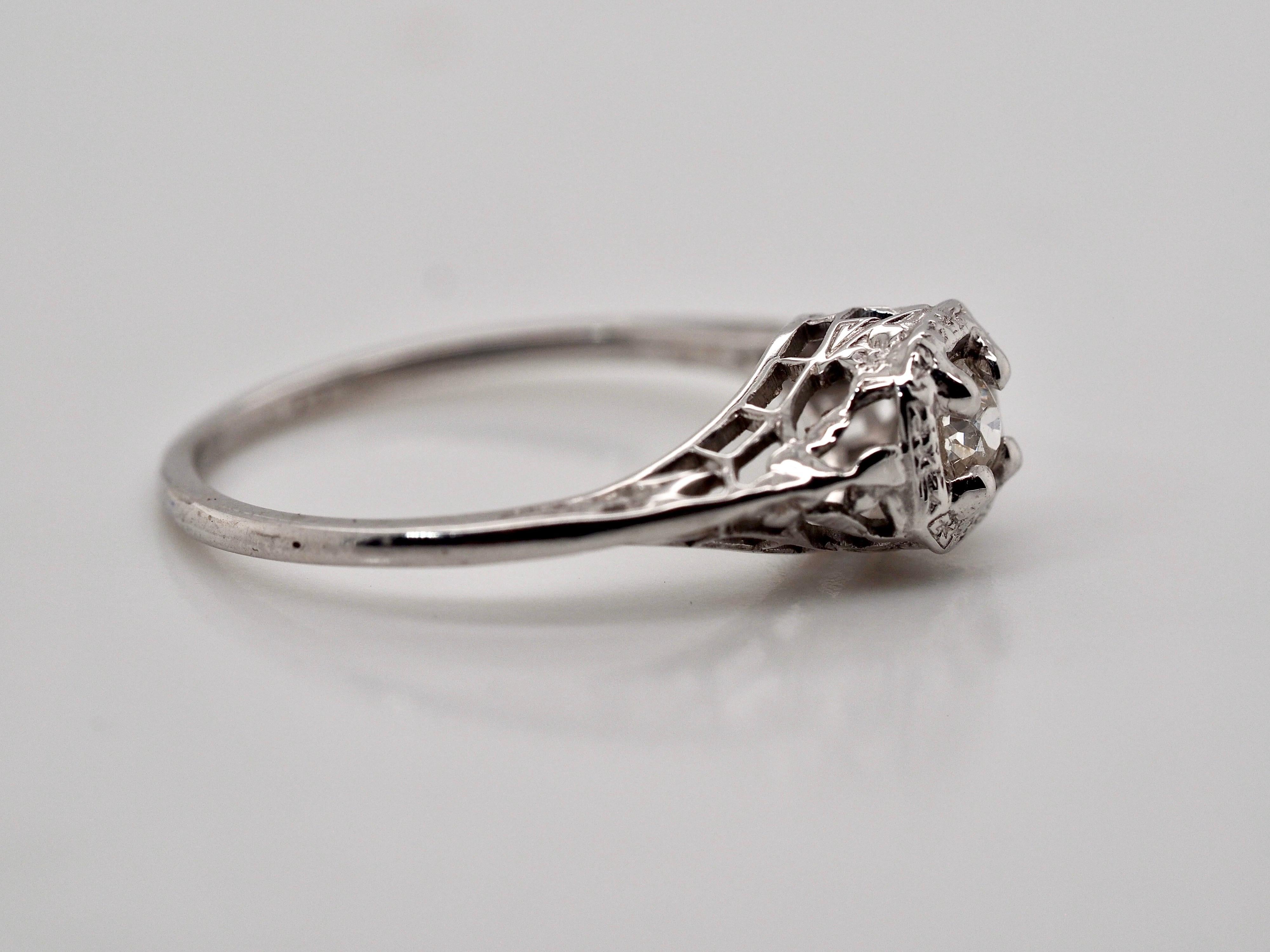 This dainty adorable 10 karat white gold Art Deco style ring features an Old Mine Cut Diamond set in four prongs with a delicate pierced gallery.  The diamond weighs approximately .15 carats; SI1  clarity J in color. Finger size 5.25 and can be