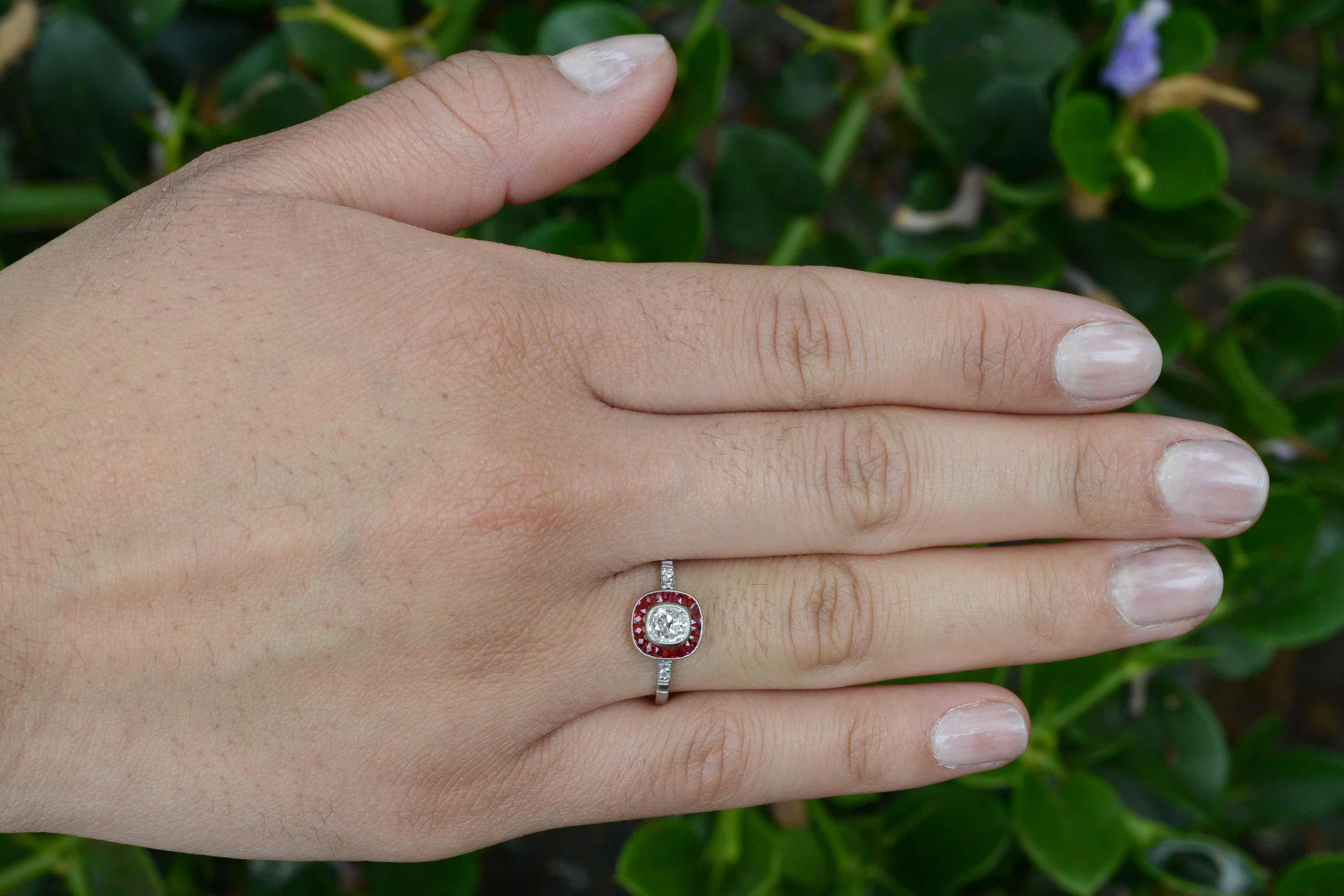 Centering upon a sparkling old mine, cushion cut diamond over 1/2 carat with those chunky facets that scatter rainbows everywhere and complemented by the velvety, rich red of French cut rubies. The amazing hand filigree under crown and milgrain add