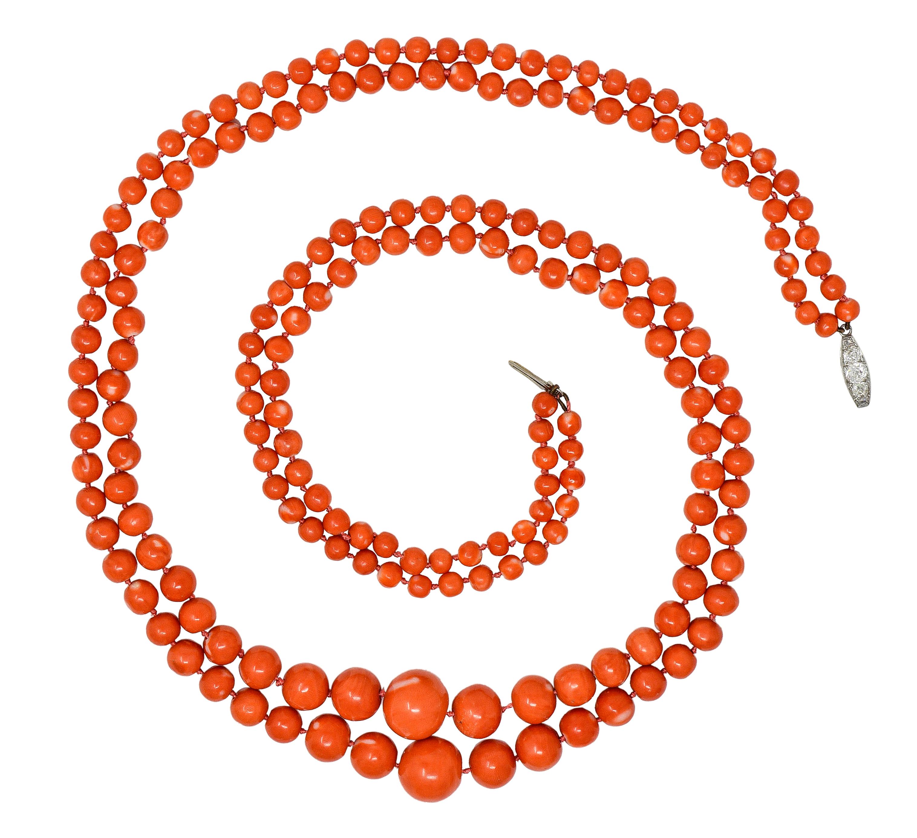 Necklace is comprised of two layered strands of round coral beads strung on knotted silk cord
Graduating in size from 5.5 mm to 15.0 mm - opaque reddish orange with white swirling
Completed by a platinum clasp closure with five old mine and rose cut