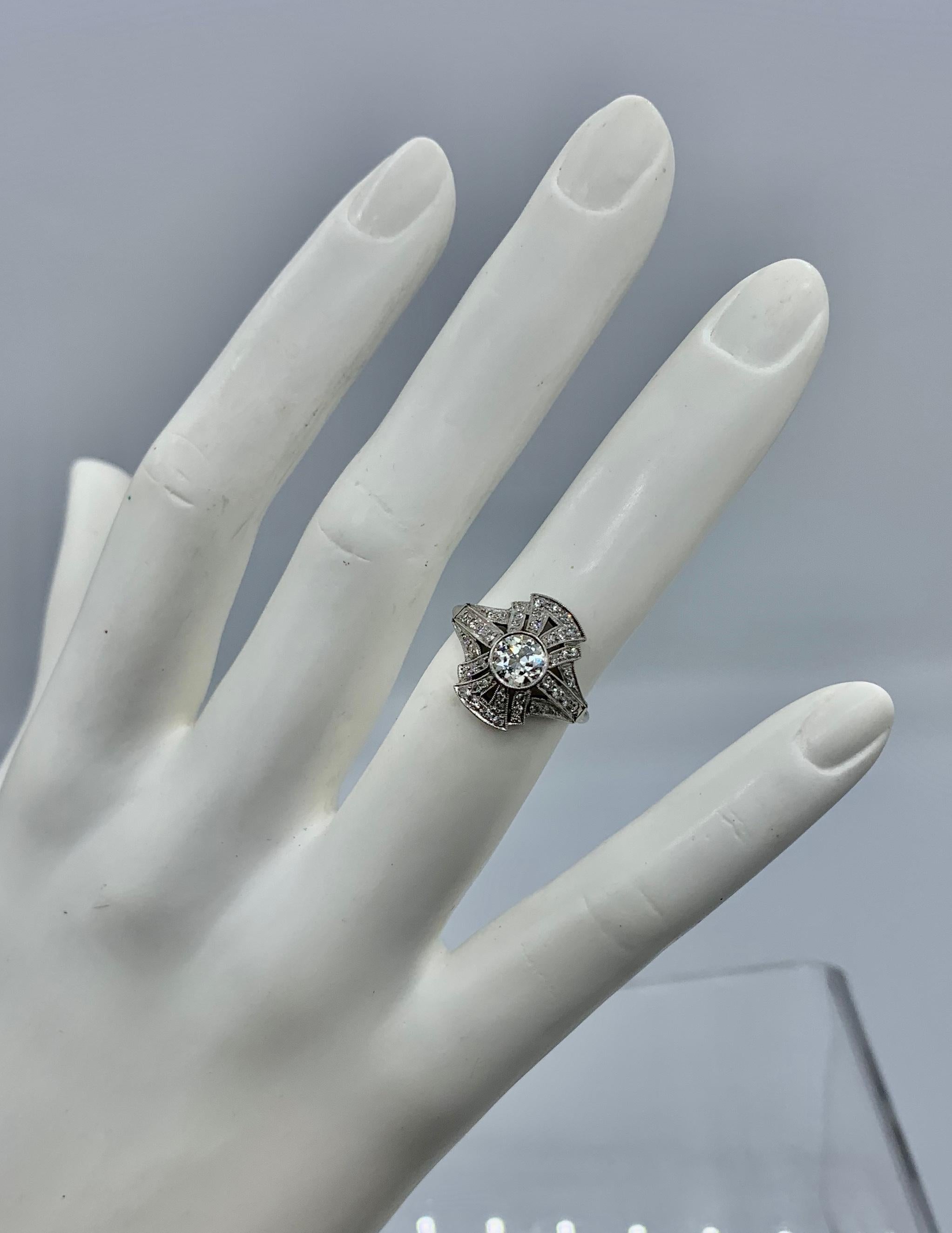 This is a stunning and dramatic Antique Art Deco Old Mine Cut Diamond Ring in Platinum with a gorgeous central .6 Carat Old Mine Diamond.  The central diamond is surrounded by a spectacular architectural design with adornments that echo the iconic