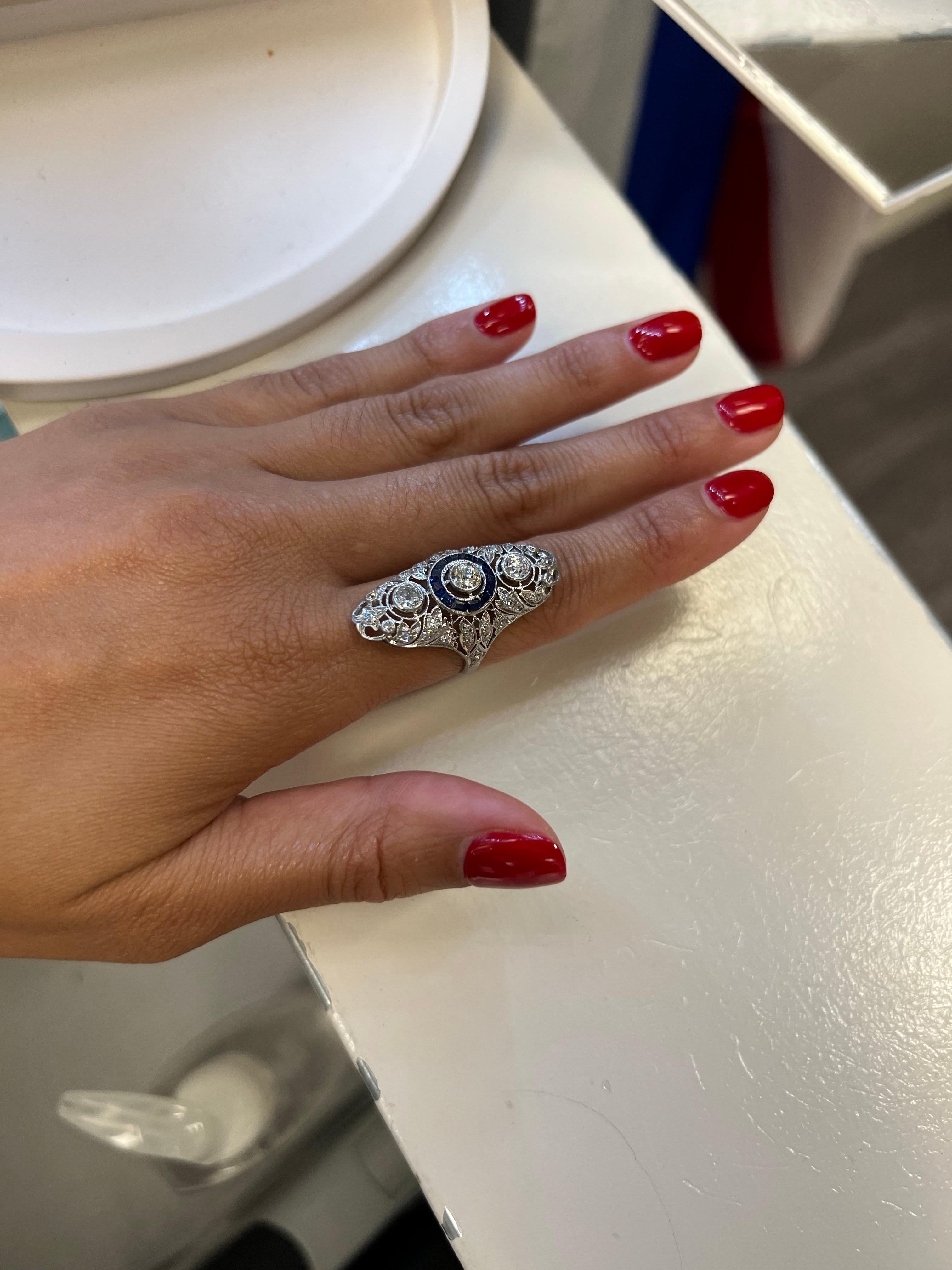 Trésor captivant de l'Art Deco, cette bague présente trois diamants taillés dans des mines anciennes, à l'éclat chaleureux et vintage, sertis dans une monture géométrique en platine finement détaillée. Une élégance intemporelle pour les