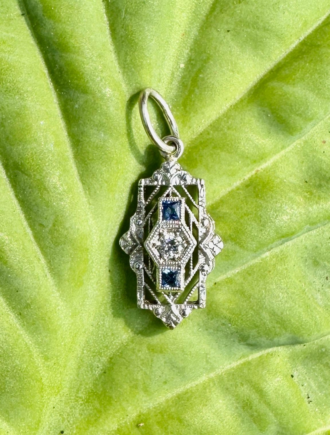 This is a very special antique Art Deco pendant with a sparkling Old Mine Cut Diamond and two square cut Sapphire gems in an exquisite delicate refined filigree design in 14 Karat White Gold.  This is one of the most beautiful Art Deco filigree
