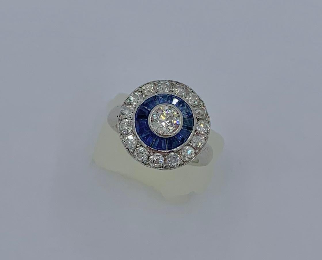 This is a stunning antique Art Deco Platinum, Diamond and Sapphire Target Halo Ring.  The ring is highlighted by very fine antique gems with brilliantly white and clean diamonds and vivid blue sapphires.  The ring is centered with a gorgeous Old