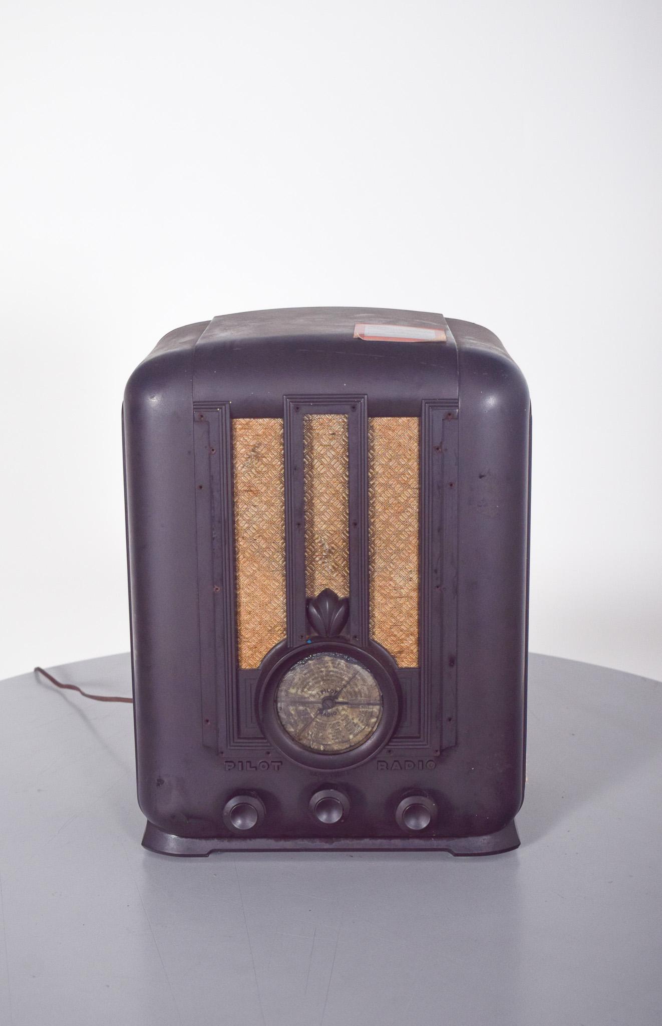 Old Pilot table radio, model 203. Old Pilot table radio, model 203. With a compact structure in dark bakelite, with a finish characteristic of the period. The front features an Art Deco design, with three vertical grilles covered in a protective