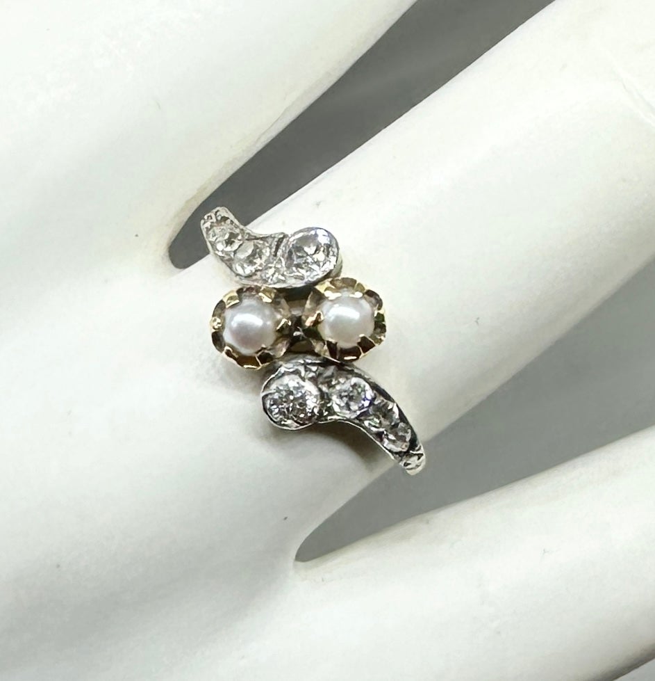 Indulge in a magnificent Antique Victorian - Art Deco Wedding Engagement Ring with gorgeous pearls and sparkling antique Old Mine Cut Diamonds set in Platinum atop 14 Karat Gold in a stunning scrolling bypass design. This rare antique jewel dates to
