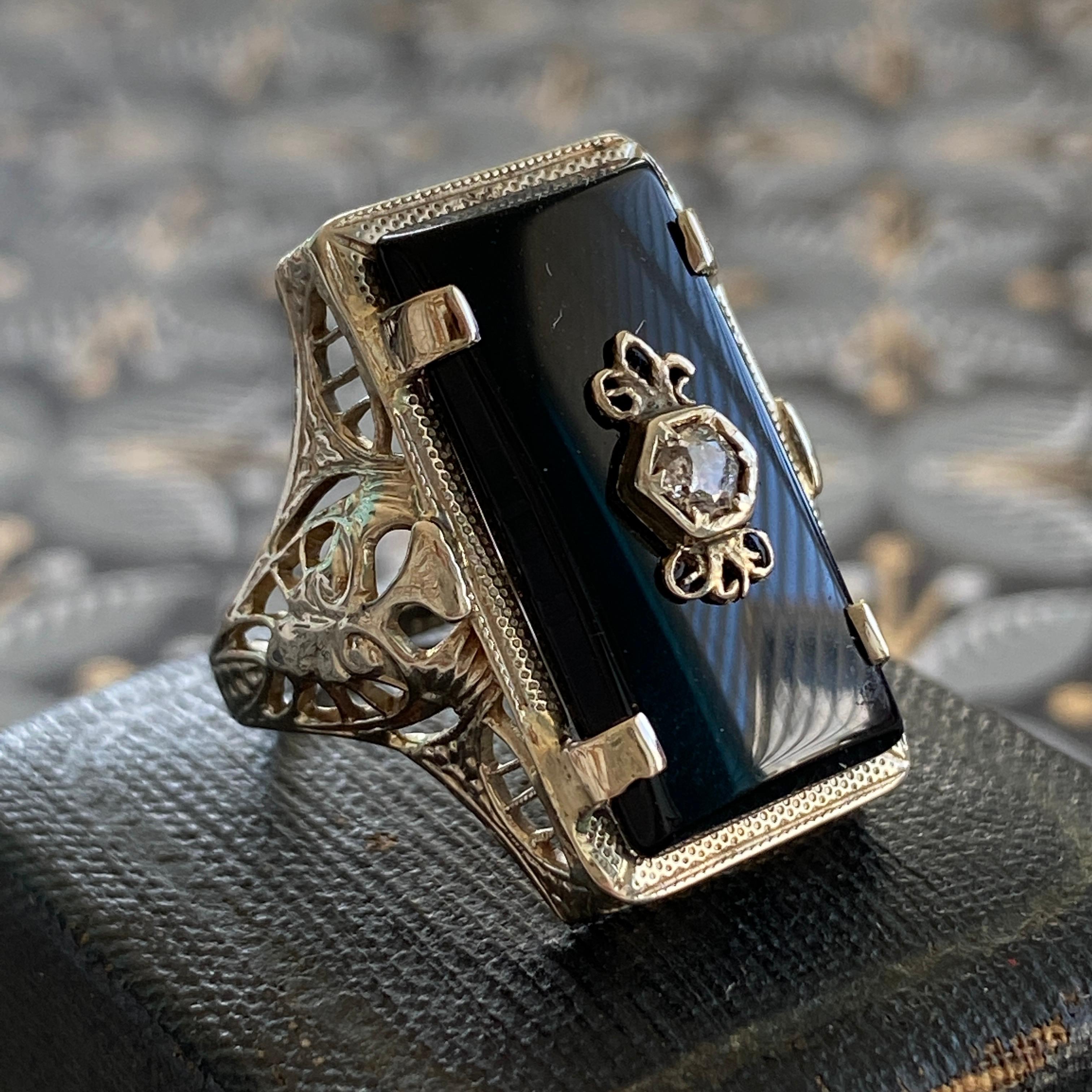 Details:
Beautiful vintage onyx set in 14K white gold filigree. The filigree has a lovely art nouveau feel. The onyx is a very rich, deep black, and a rose cut Diamond is set in the center of the onyx stone. Hallmarks on the interior band read P&KCC