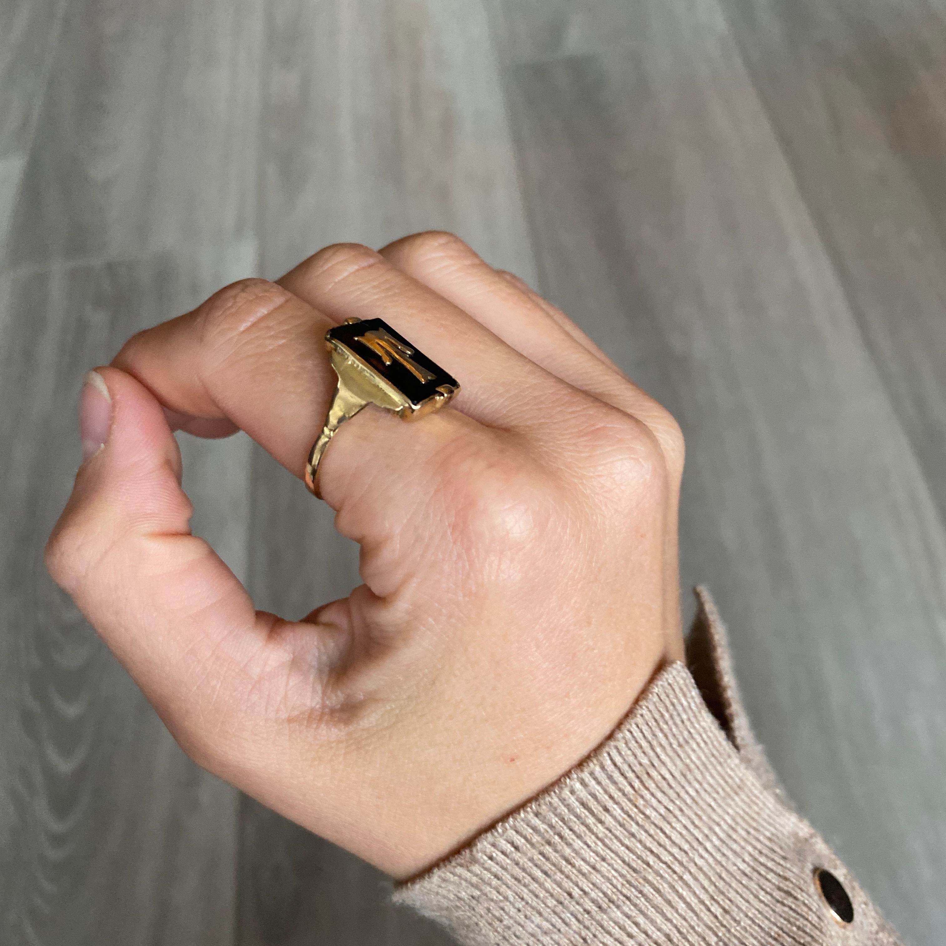 This ring holds a rectangular Onyx which has the letter 'T' that lays over the top. The shoulders have classic art deco step style to them. Modelled in 9carat gold. 

Ring Size: P or 7 3/4
Face Dimensions: 15x11mm

Weight: 3.3g