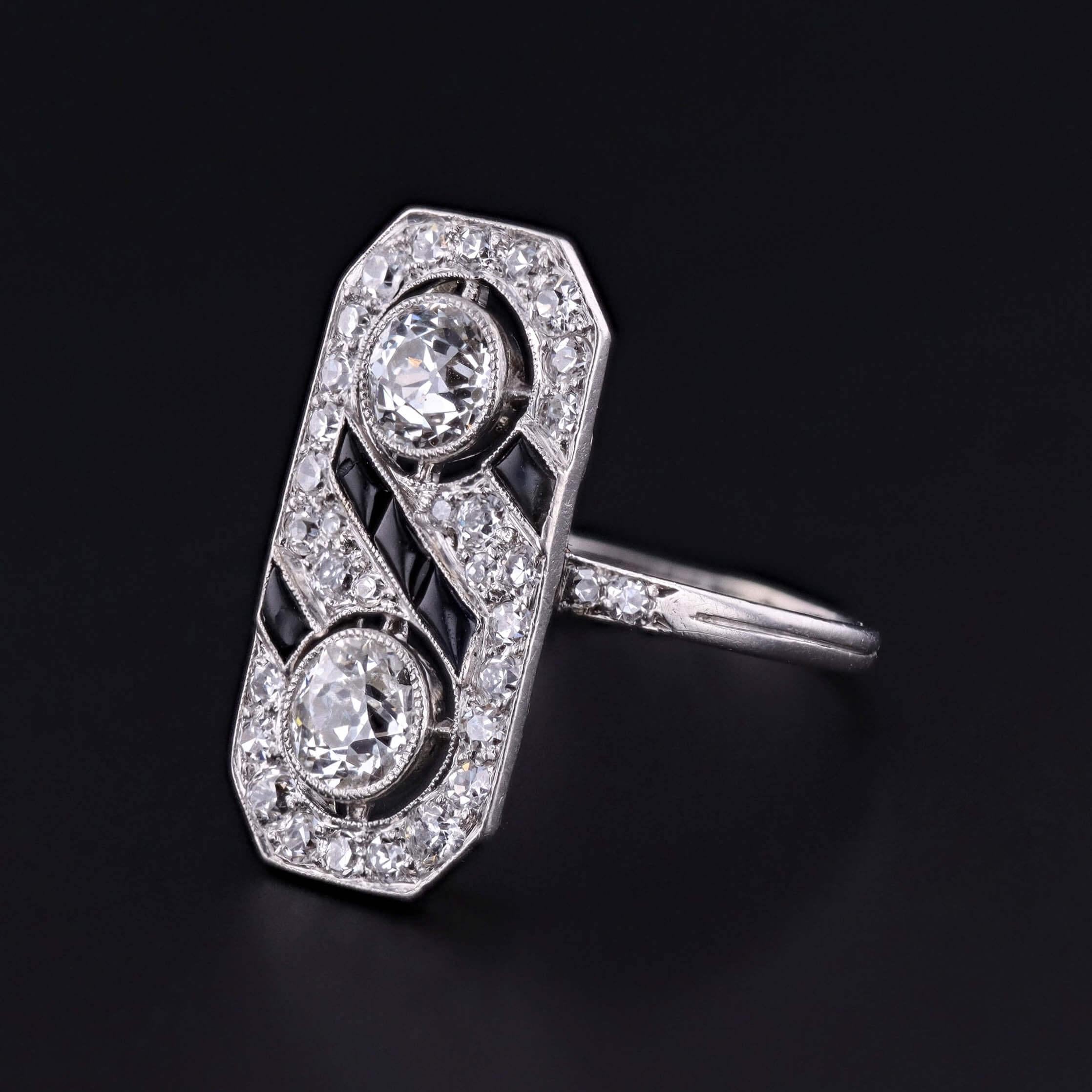 Une étonnante bague Art déco en platine des années 1920, présentant d'audacieuses bandes d'onyx noir contrastées par une élégante rangée de diamants scintillants.  La bague de cocktail rectangulaire présente deux diamants de taille européenne