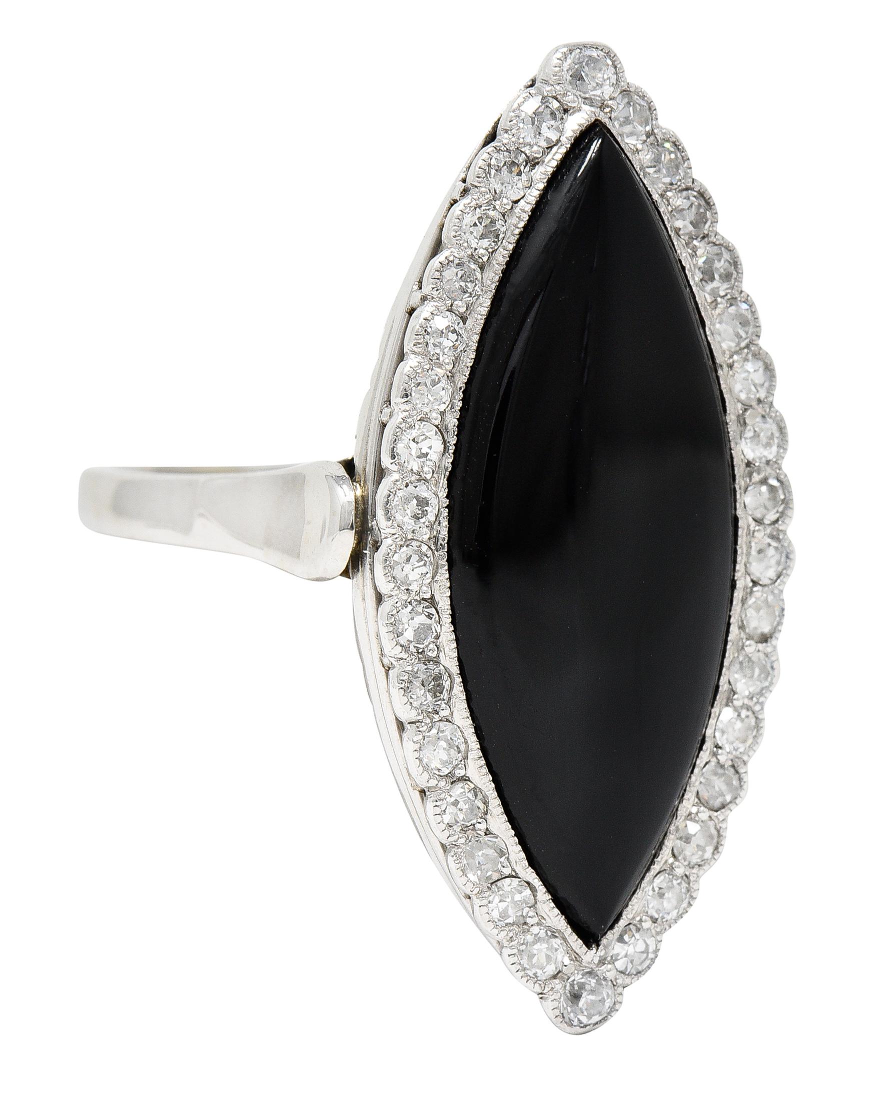 Ring is designed as a substantial navette form. Featuring navette shaped calibrè cut onyx measuring approximately 27.5 x 11.0 mm. Opaque black with excellent polish. Surrounded by a halo of old European and single cut diamonds. Weighing in total