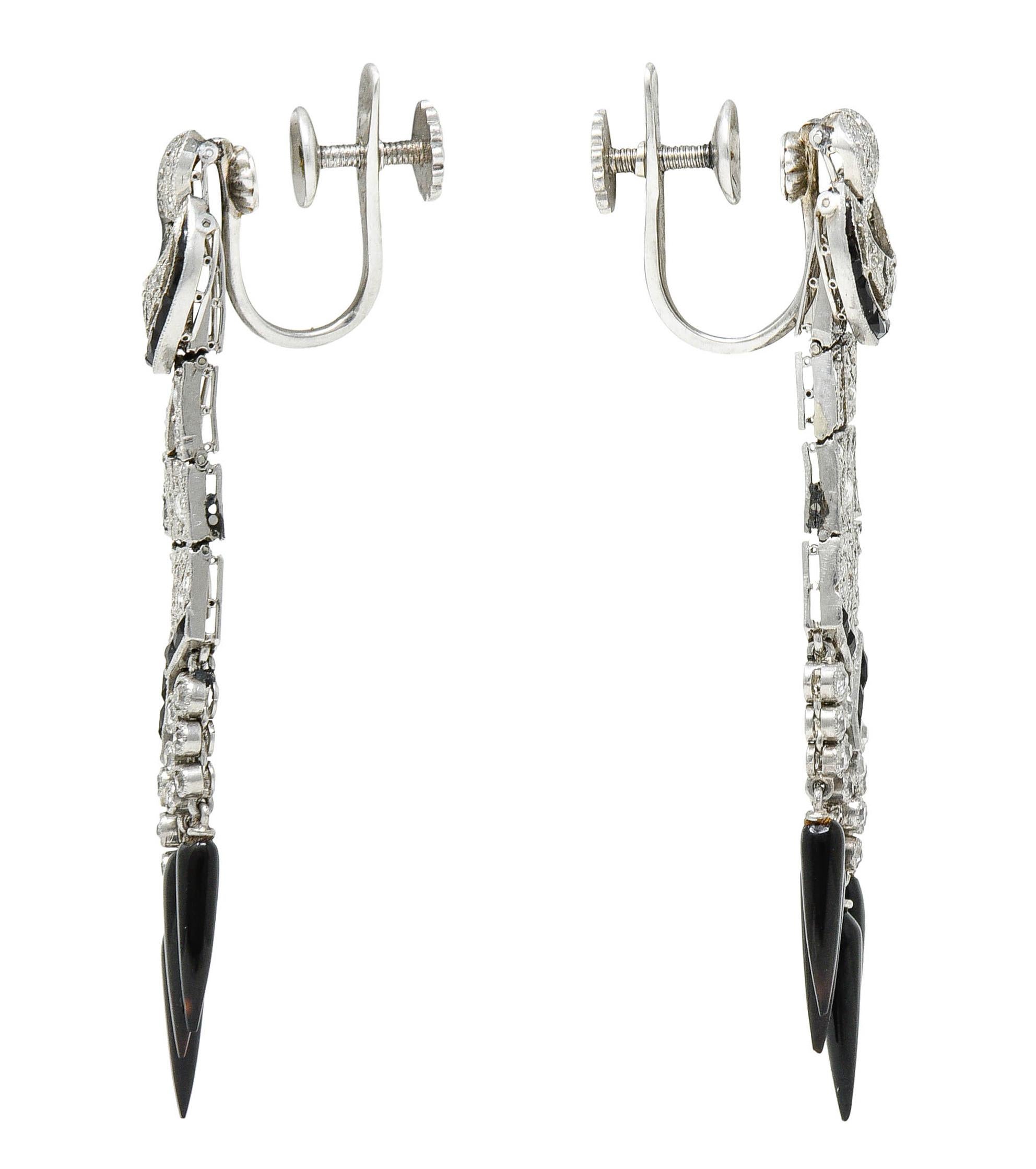 Tassel style earrings are comprised of articulated drops topped with an articulated buckle motif

Accented by calibrè cut onyx and terminating as onyx pointed pampel drops

Set throughout by single, rose, and transitional cut diamonds

Weighing in