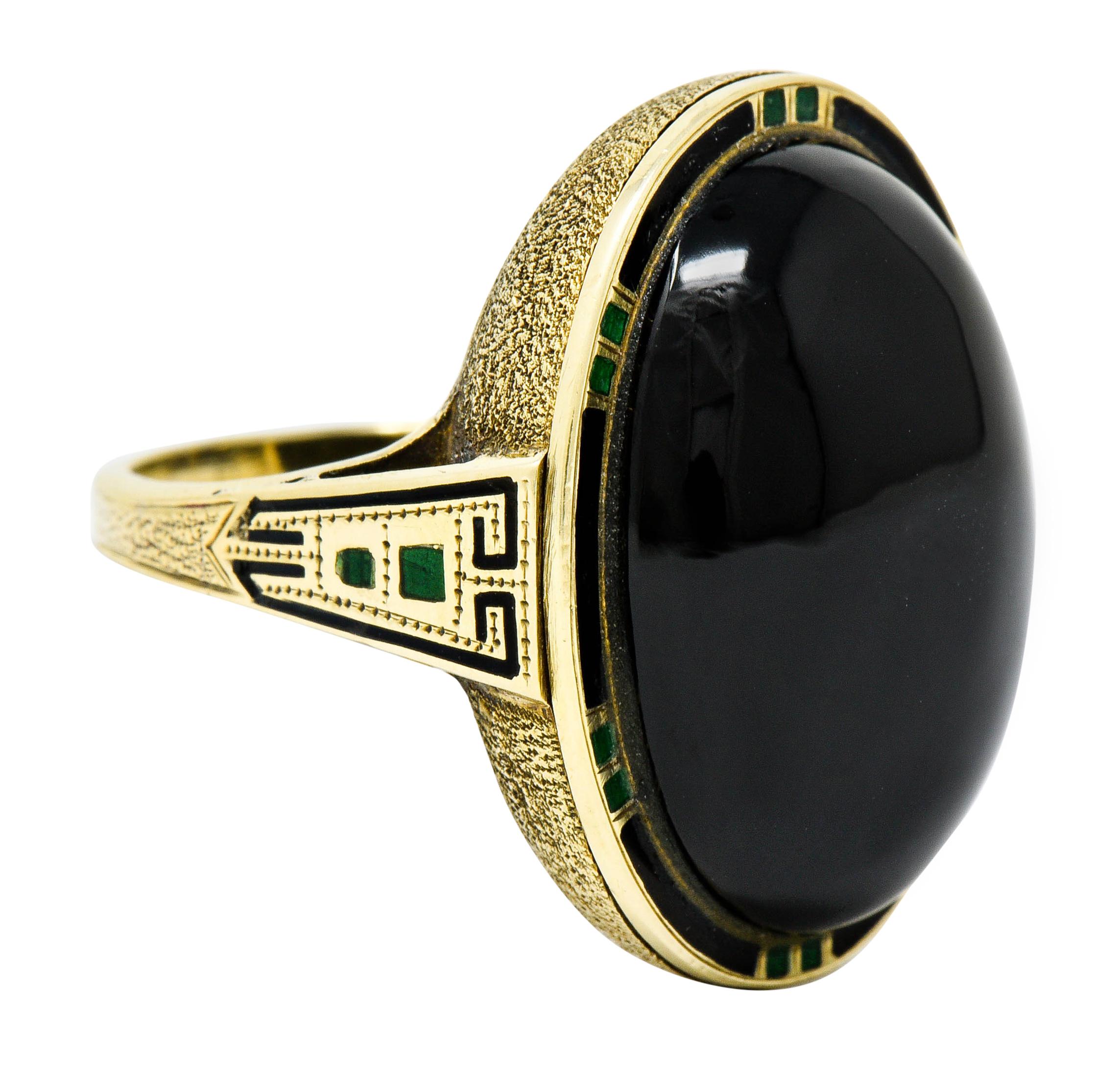 Centering an oval onyx cabochon measuring approximately 21.7 x 16.4 mm

Surrounded by a delicate black enamel halo with green dash accents

Mounting features a stippled texture while shoulders feature a Greek key motif

Enamel is excellent overall