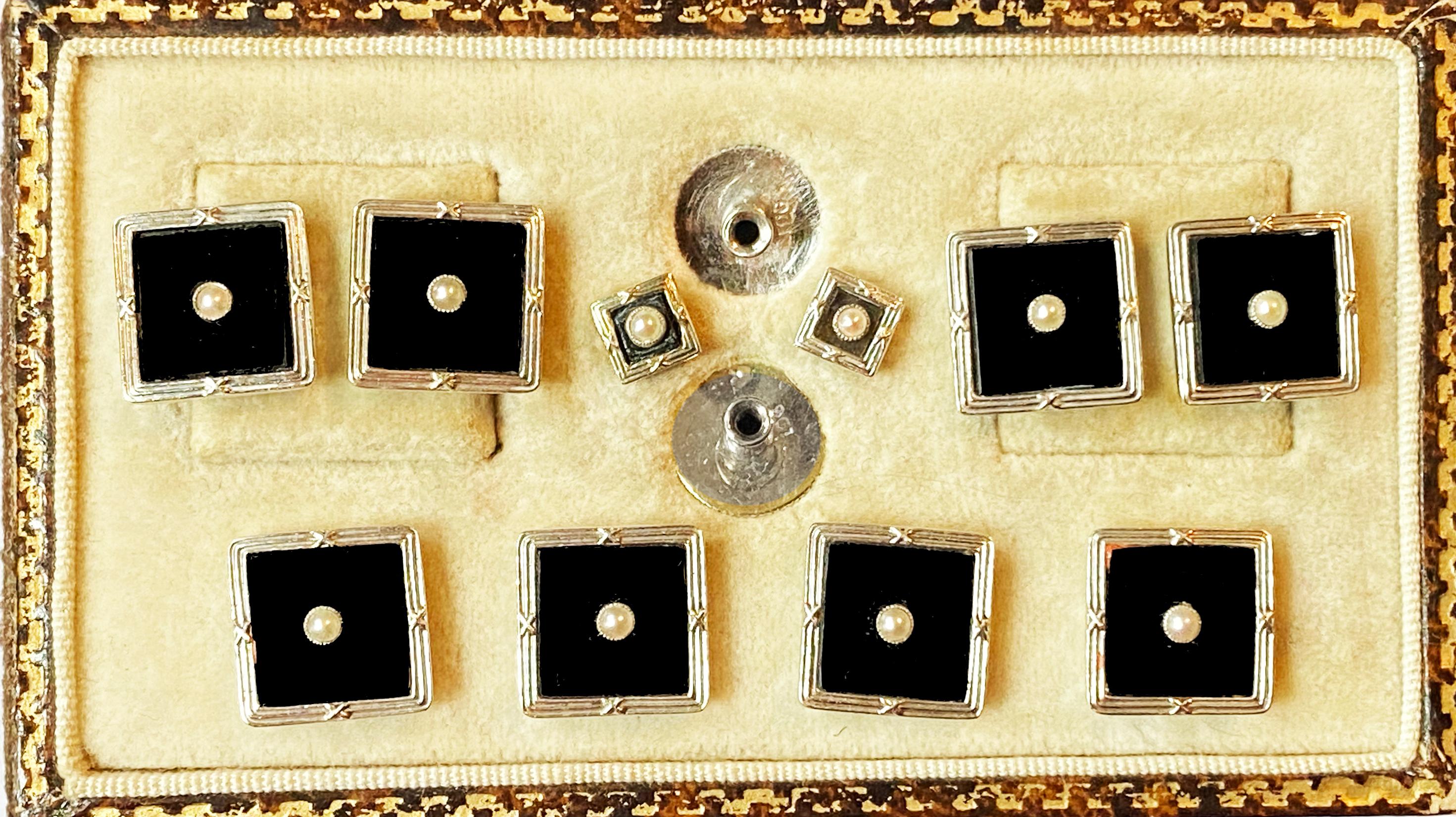 Art Deco onyx and 9ct white gold cufflinks studs tuxedo set in fitted box, English C.1920. The studs of square shape, black onyx centre, gold surround, the centre of each with a small pearl. The cufflinks with link between, collar studs set with