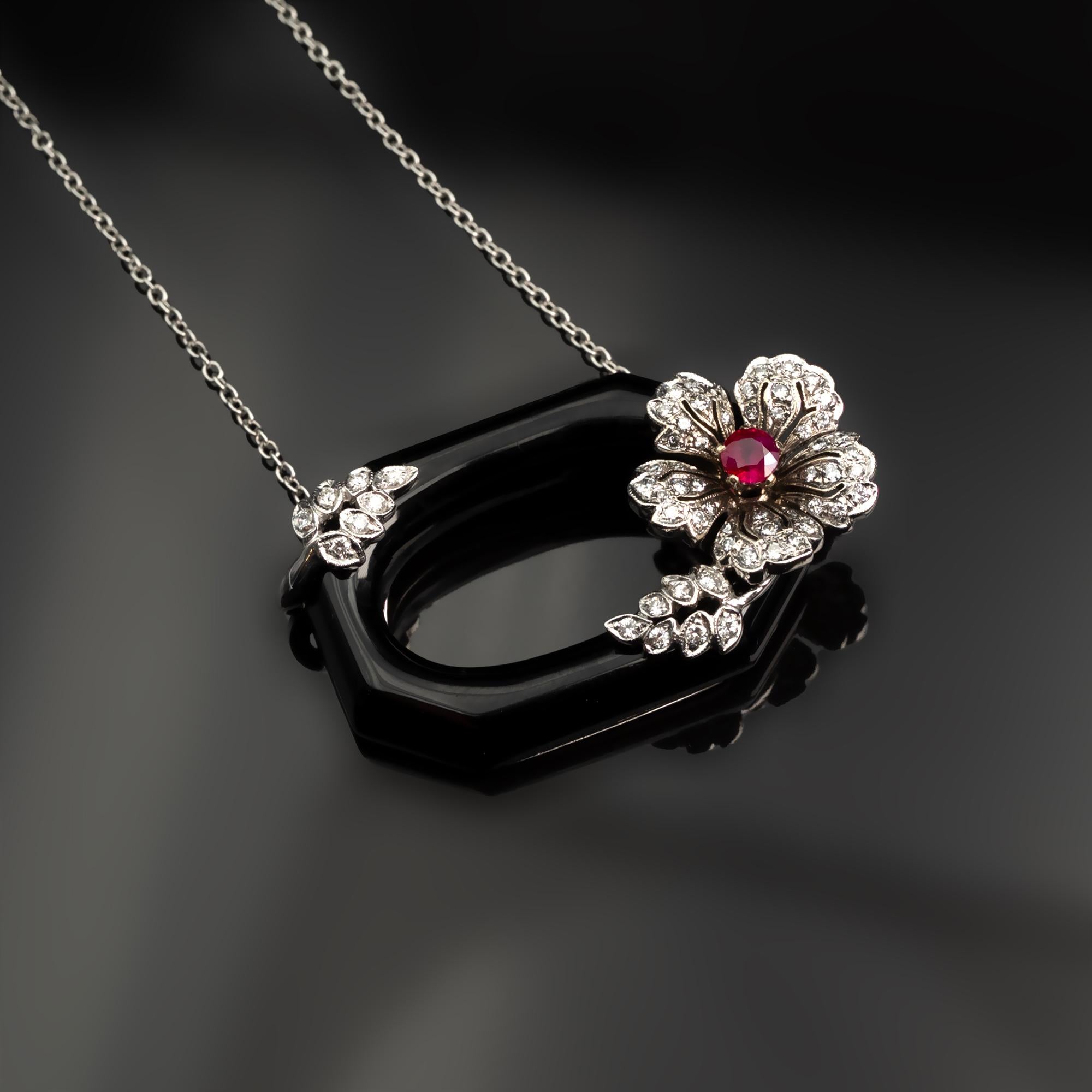 Lovely necklace consisting of a geometrical carved black onyx on which a white gold and diamond flower and leaves are wrapped. In the center of the flower, a vid red ruby is set.
The make is excellent, as well as the quality of gemstones used; a