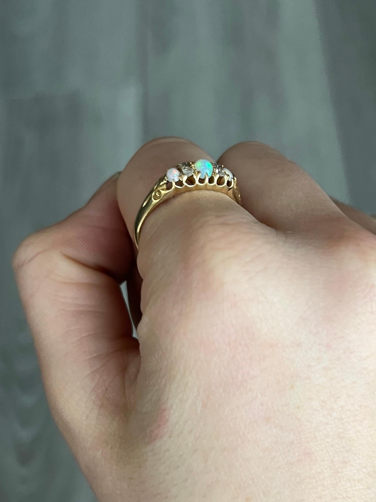 Die Opale in diesem Ring mit drei Steinen spiegeln wunderbare Farben wider, und zu beiden Seiten des zentralen Steins sitzt ein Paar Diamanten. Sie sind in einfachen Krallenfassungen gefasst und alle in 18-karätigem Gold modelliert. Vollständig