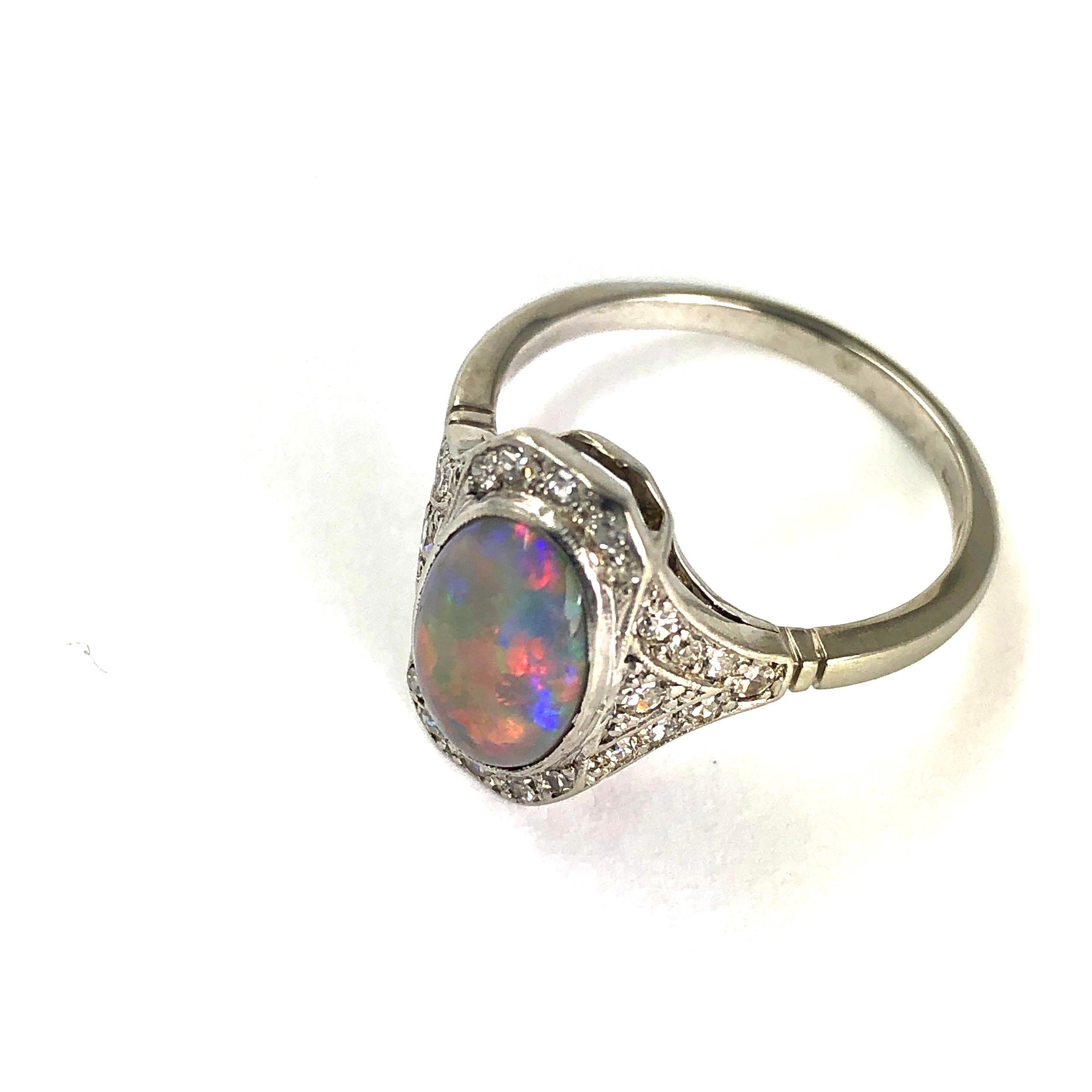 This show stopping piece holds an opal which measures approximately 2cts. The opal has so many fleck of colour that appear as it is moved in the light. The pictures do not do it justice! Around the central stone is a halo of old European cut