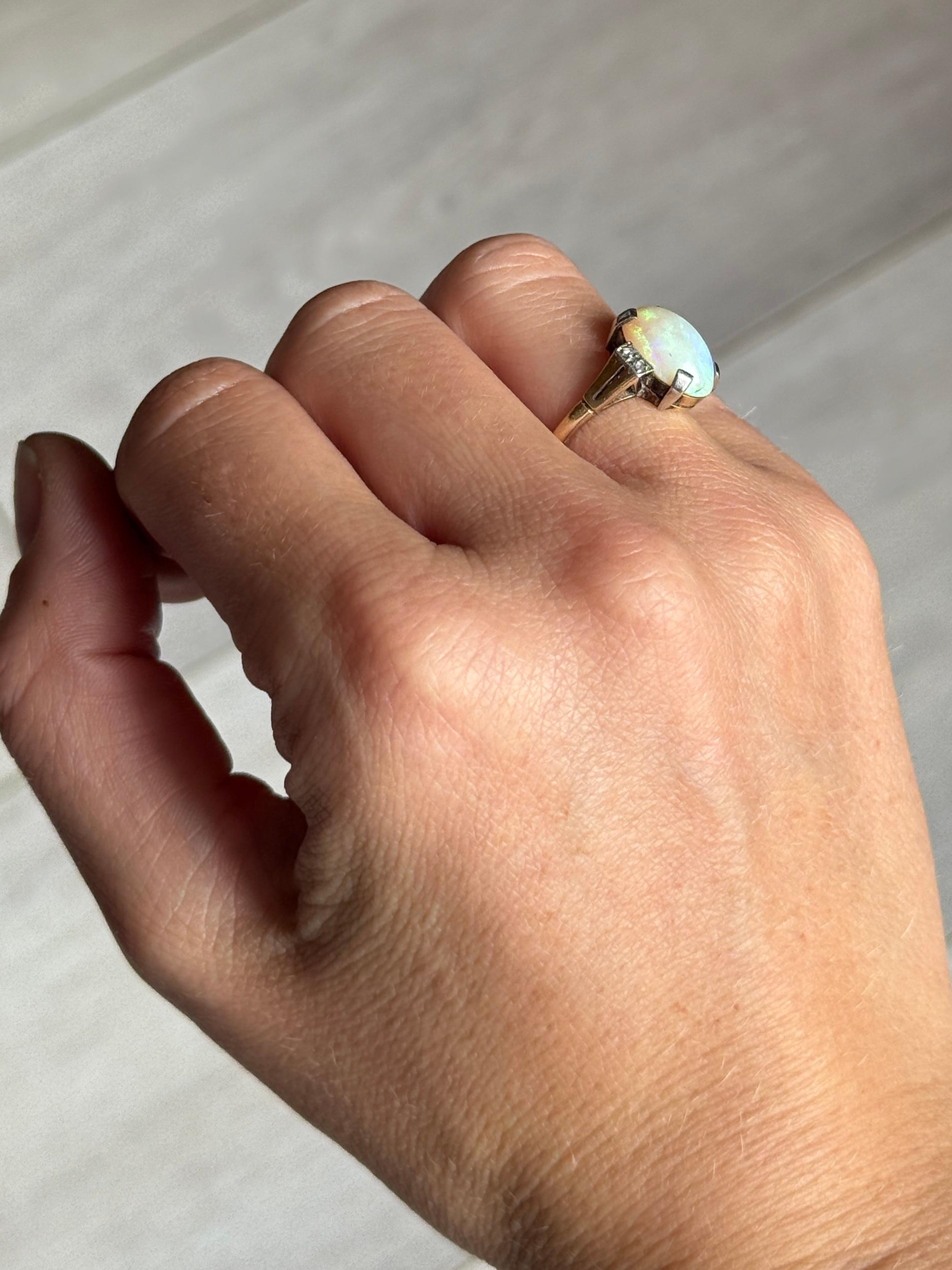 L'opale è di colore pallido e presenta molti lampi di colore.  verde e tutti gli altri colori al suo interno. I diamanti taglio rosa ai lati dell'opale hanno un totale di 4 punti per lato. L'anello stesso è realizzato in oro 9ct. 

Misura