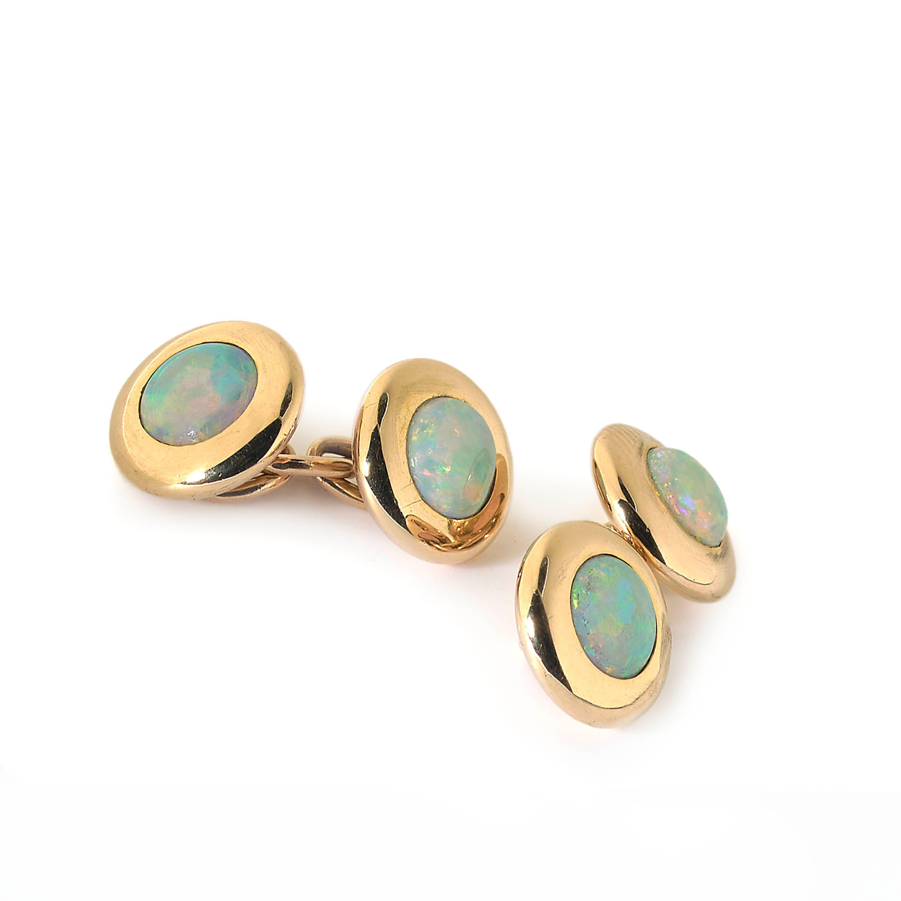 A pair of early twentieth century opal and gold cufflinks, with a single, round cabochon opal in each head, within a broad gold, domed surround, with chain link fittings, with French, shell marks, for 14ct gold, stamped more recently, for retail in