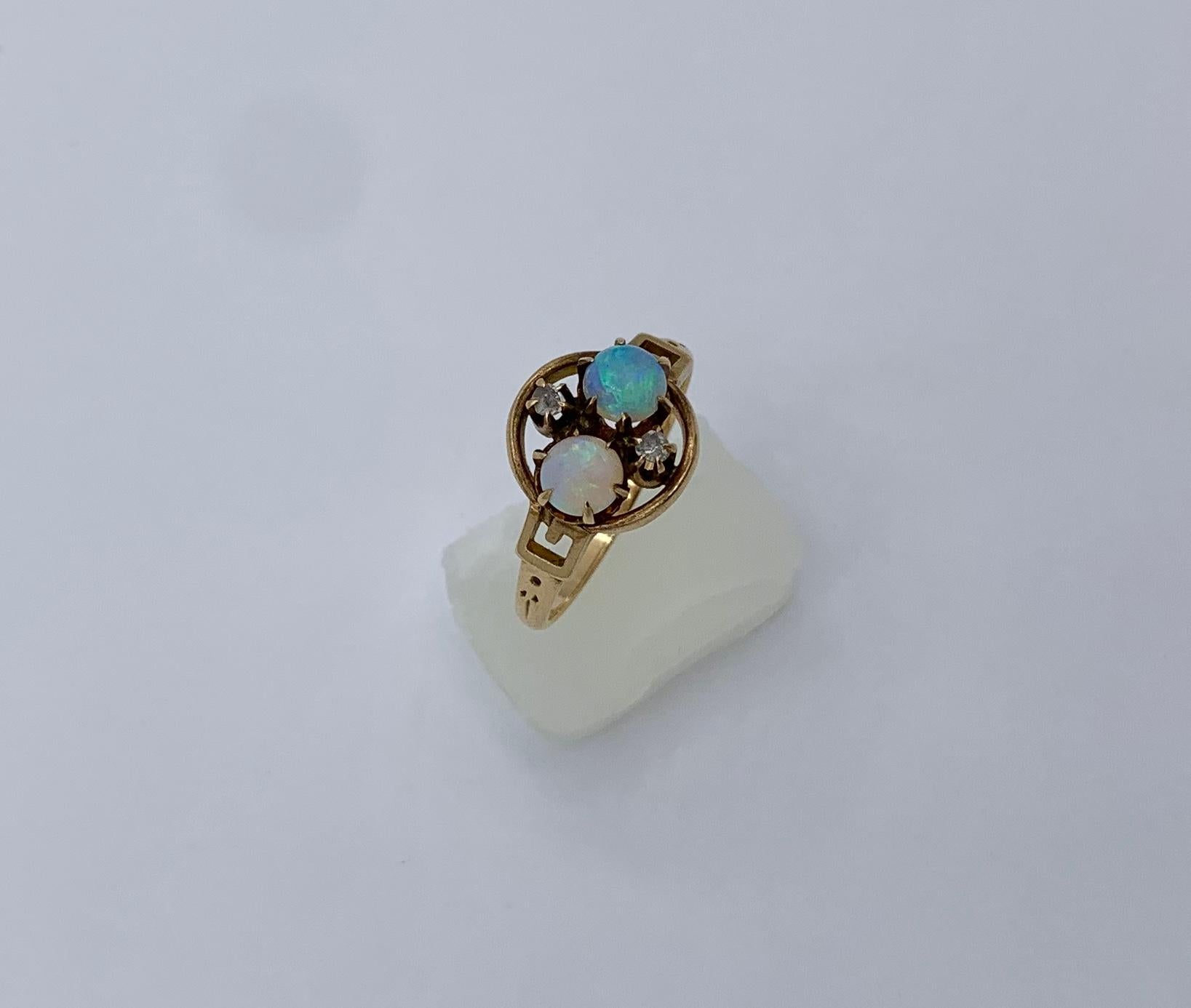 An Antique Victorian - Art Deco Ring with two gorgeous natural round Opals and two Old Mine Cut Diamonds of stunning beauty. The opals have yellow, green, and blue fire.  The two Opal gems are accented by two sparkling Old Mine Cut Diamonds.   The