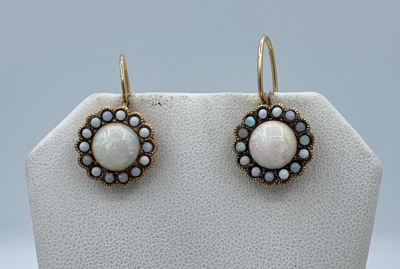 A gorgeous pair of antique Art Deco Opal Earrings with spectacular round Opal cabochons of great beauty surrounded by a halo of smaller opal cabochons set in 14 Karat Gold.  The colors in these Opals are vivid blues and greens, yellows, oranges and