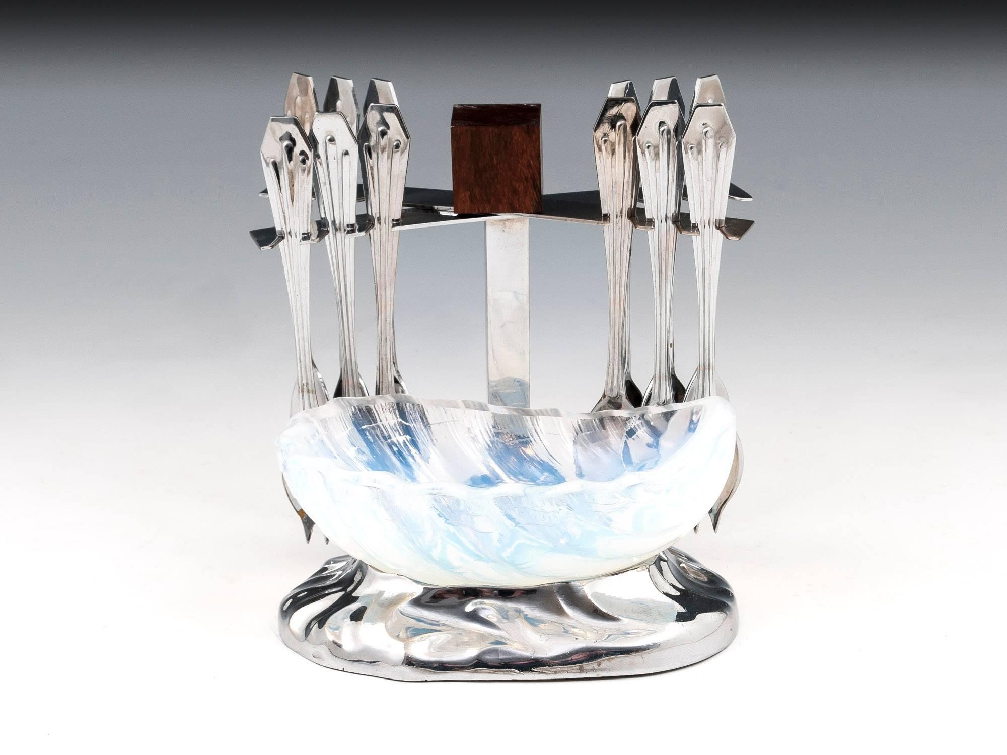 Art Deco oyster spoon set by Jaque Adnet comprising twelve silver plate spoons housed in a plated stand with a shaped base and stunning opalescent oyster bowl, the top of the stand has a Macassar ebony block for ease of handling.