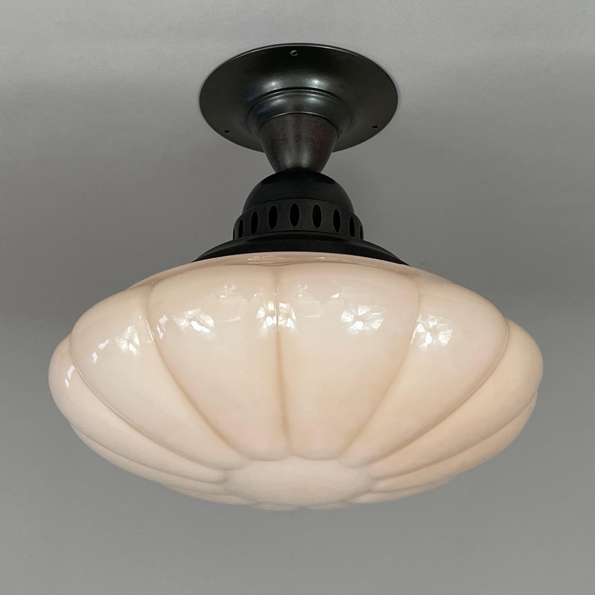 Cet élégant plafonnier a été conçu et fabriqué en Allemagne au cours de  l'époque de l'Art déco.

Ce luminaire est doté d'un abat-jour en verre opalin légèrement festonné, en forme de melon, d'une couleur rose pâle chaude et crémeuse, associé à un
