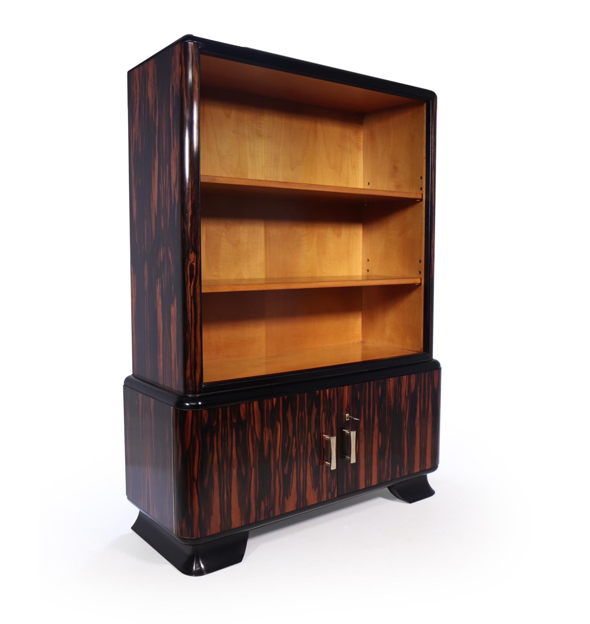 A very attractive open bookcase in macassar ebony with lockable cupboard below, two adjustable height shelves rounded corners and polished bronze handles the cabinet is excellent quality and has been fully re finished to a very high standard makers
