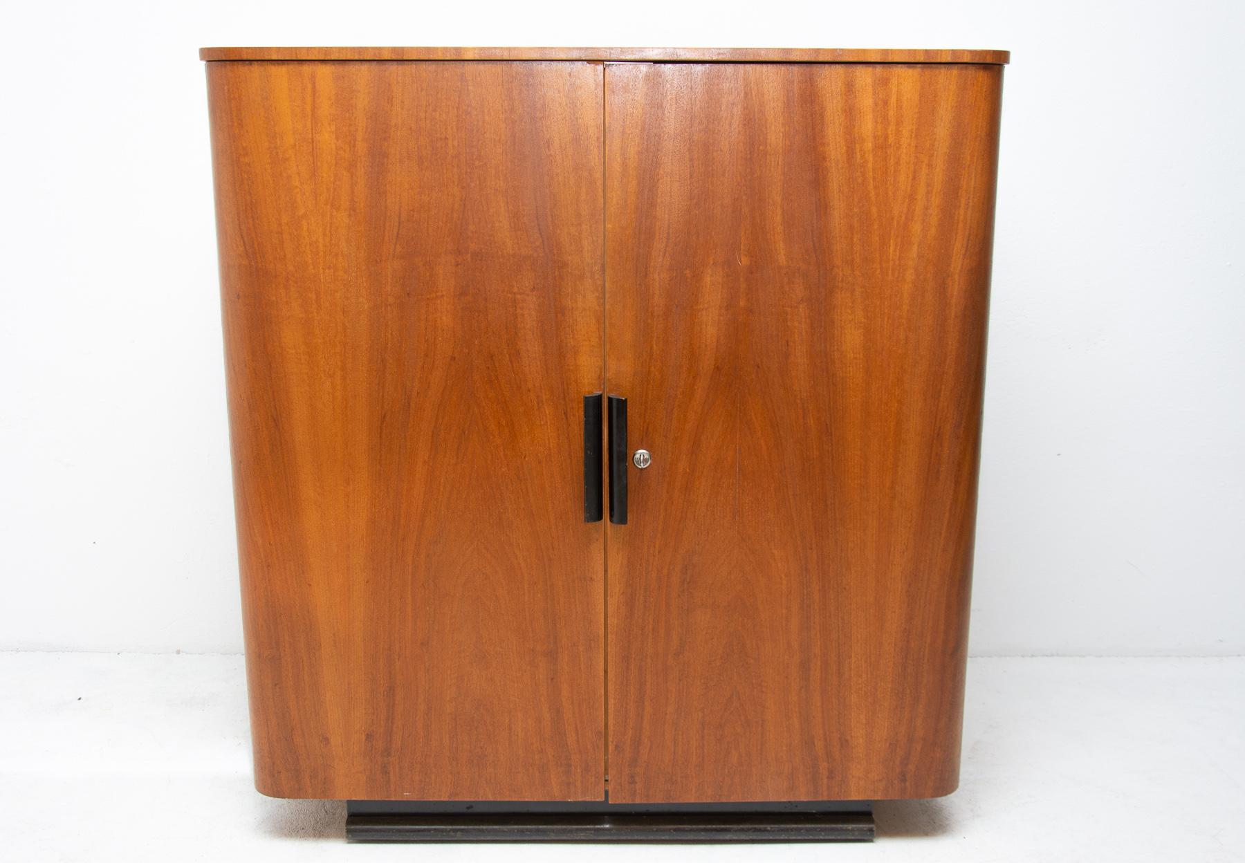 This walnut cabinet, small wardrobe or secretary it can be used for bedding, clothes, documents, papers etc. It´s part of a complete bedroom suite by Jindrich Halabala, circa 1940. Black painted pedestal, and handles. Inside the cabinet are four