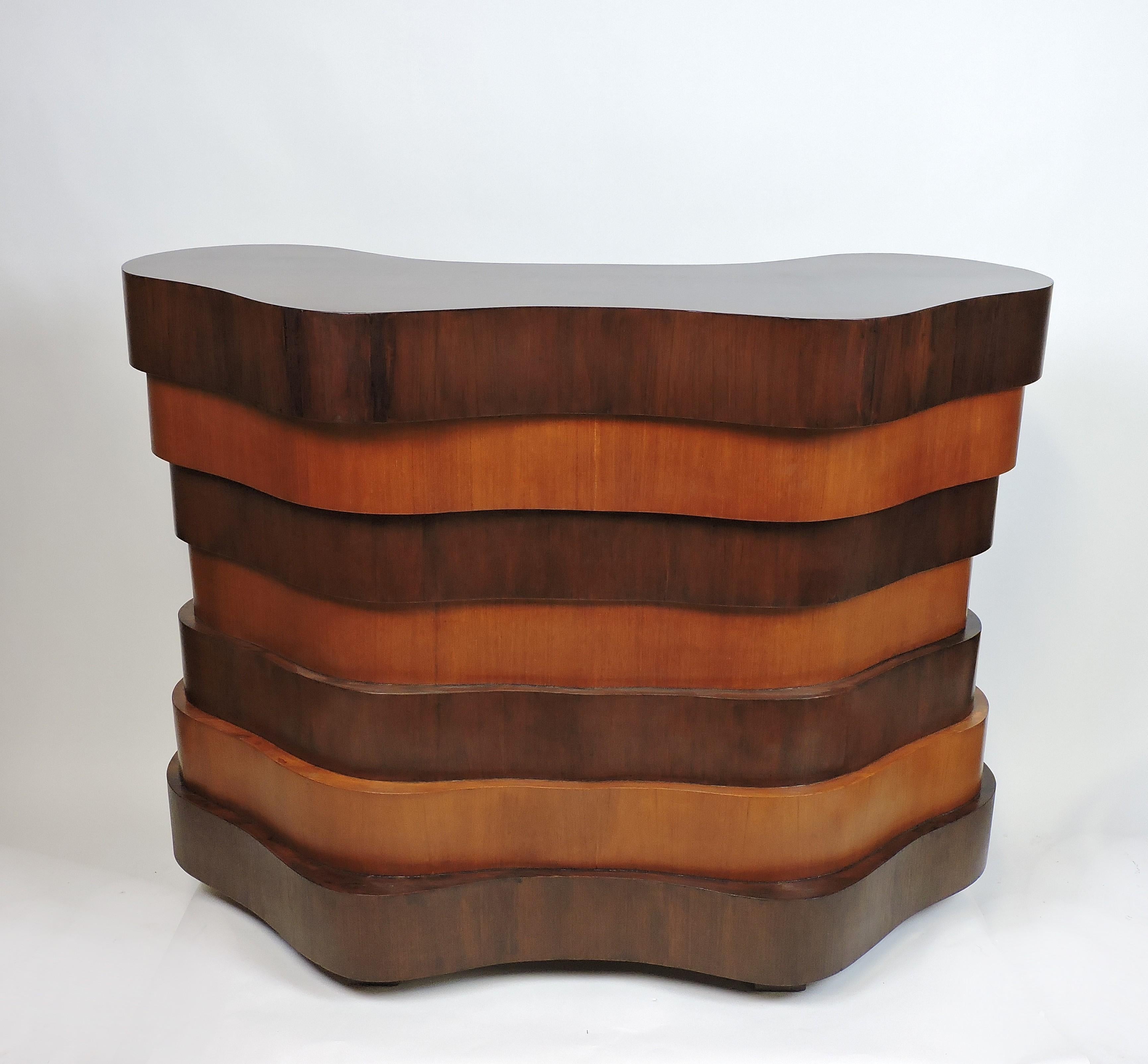 Stunning and unique Art Deco or Mid-Century Modern dry bar in a curvaceous, stepped design. This bar has layers of curved shapes alternating in a dark and light toned wood pattern. In the back there are three shelves for storage and two doors with