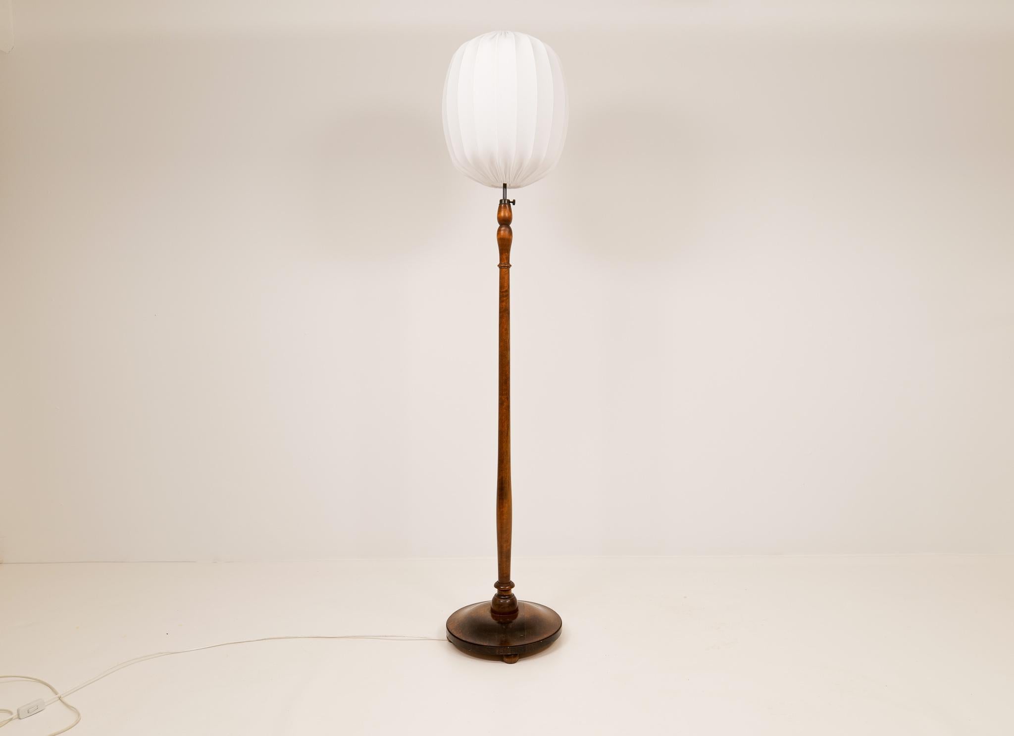 Nice looking organic floor lamp with a base and the rod in stained birch. The lamp can be adjustable in length and are easy to handle with the rounded metal that is placed on top of the lamp.

Good vintage condition with some wear. Small crack on
