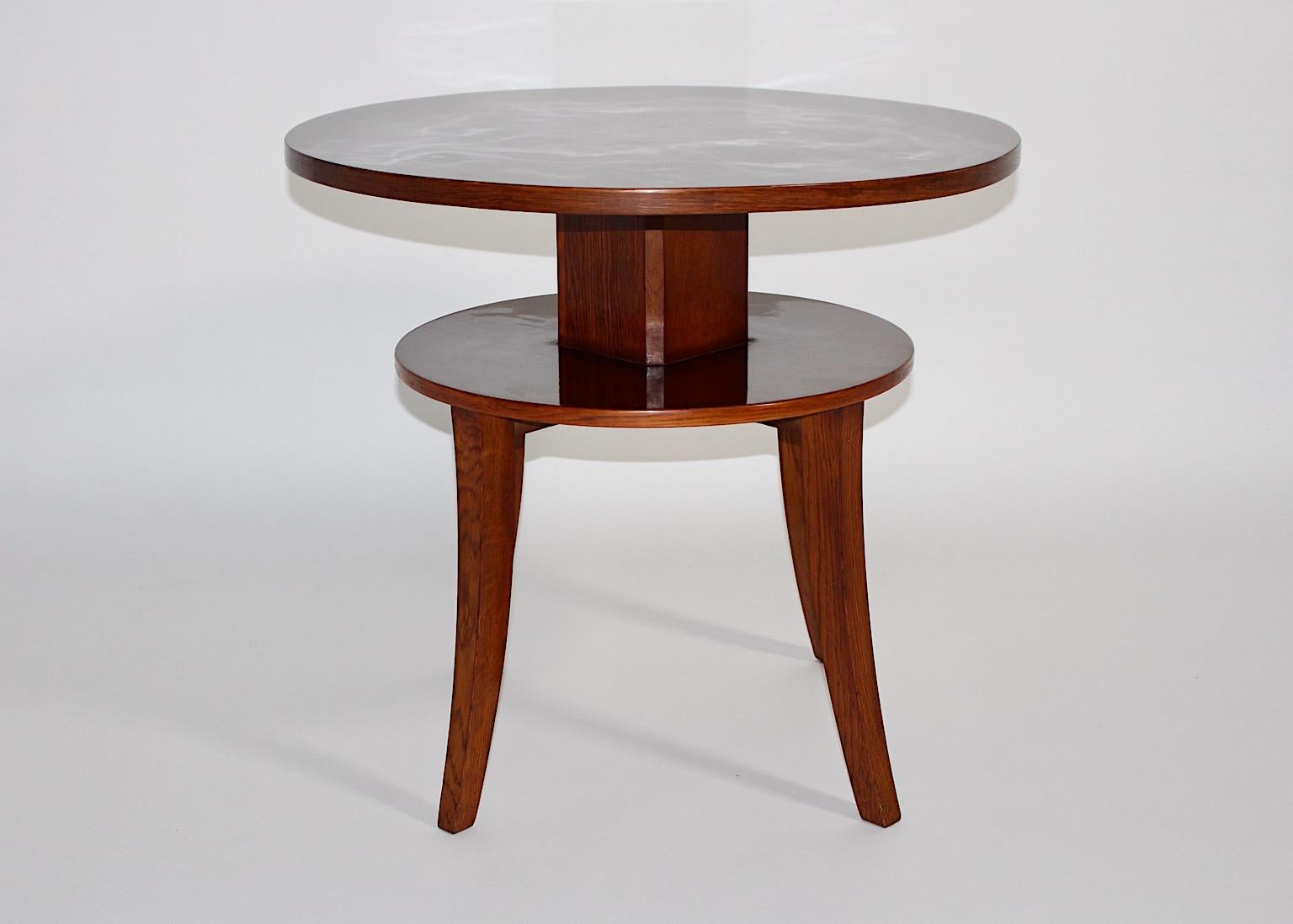 Art Deco organic circular two tier coffee table or side table from walnut and oak circa 1925 Vienna.
An amazing coffee table or side table from walnut and oak with two tiers and slightly curved legs. Both tops are connected with a squared stem.
With