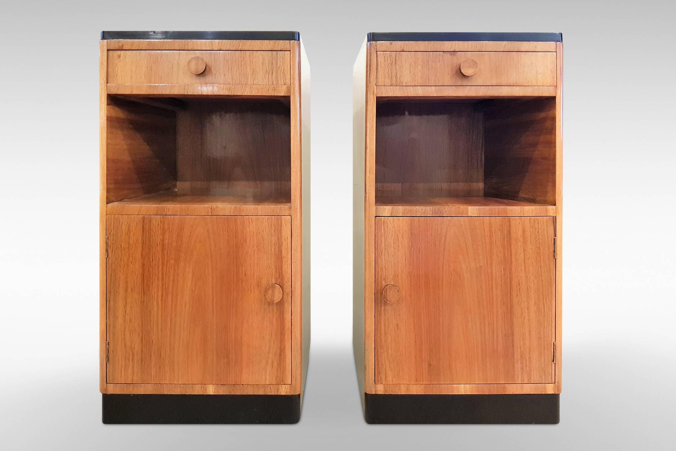 A handsome pair of original Art Deco bedside cabinets in figured and straight grain walnut veneers with ebonized detailing. In a modernist influenced design typical of the mid-late 1930s, these are high quality pieces with handmade dovetail joints