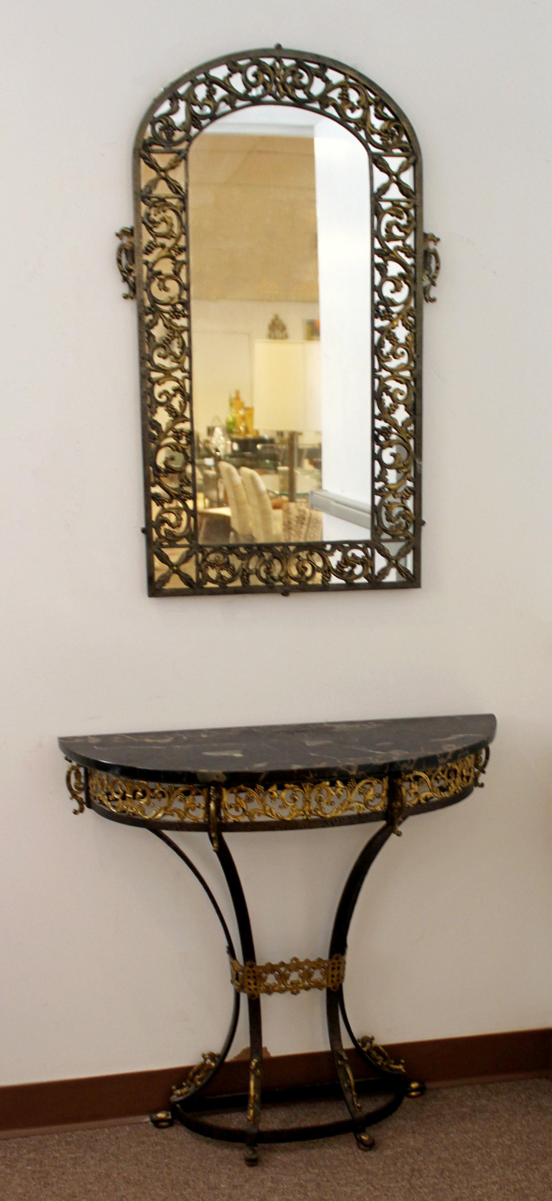 For your consideration is a stunning, hammered and gilt, wrought iron console table and matching mirror, with a black marble top, attributed to Oscar Bach, circa the 1920s. In excellent condition. The dimensions of the table are 31