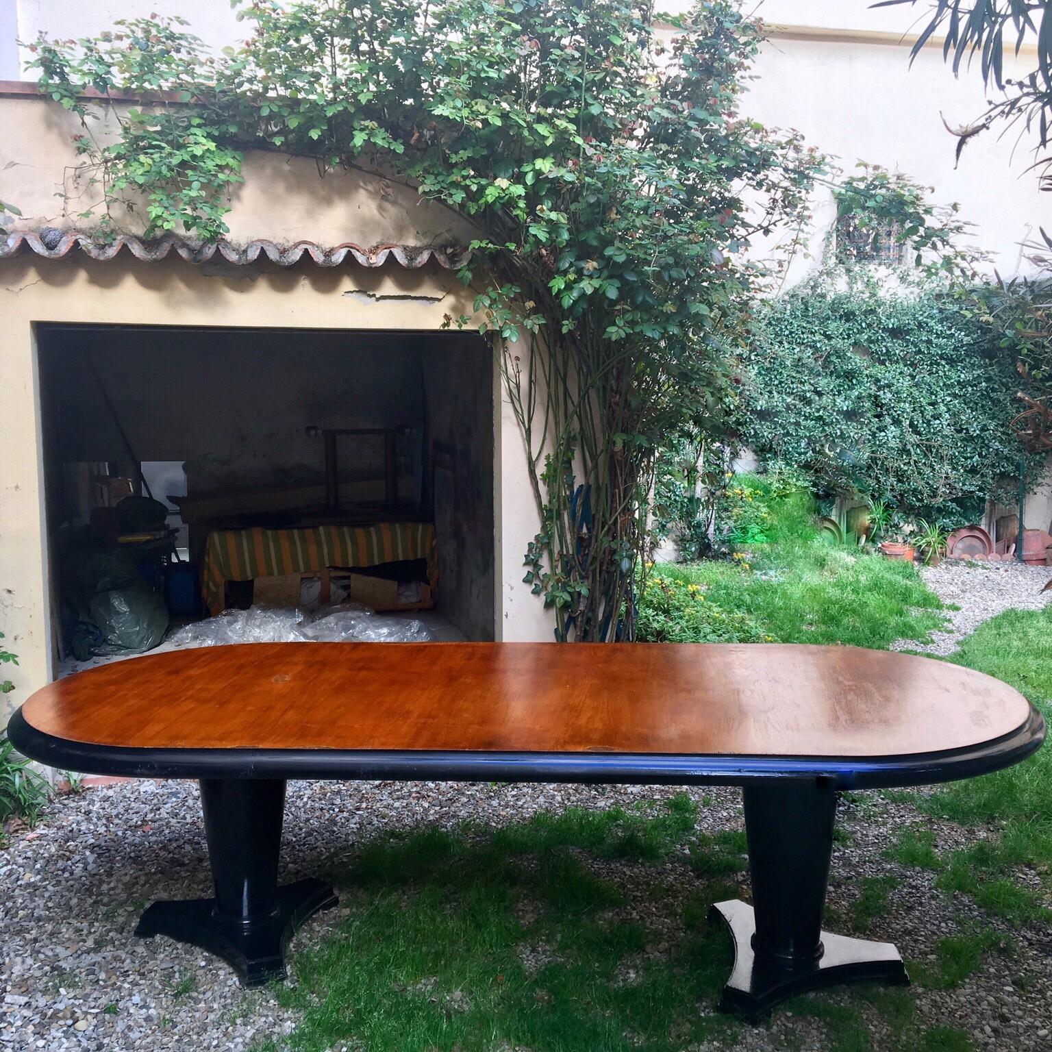 Art Decò oval dining table in mahogany wood with black ebonized edge. The two pedestal bases are in ebonized black wood and they have a conic shape.