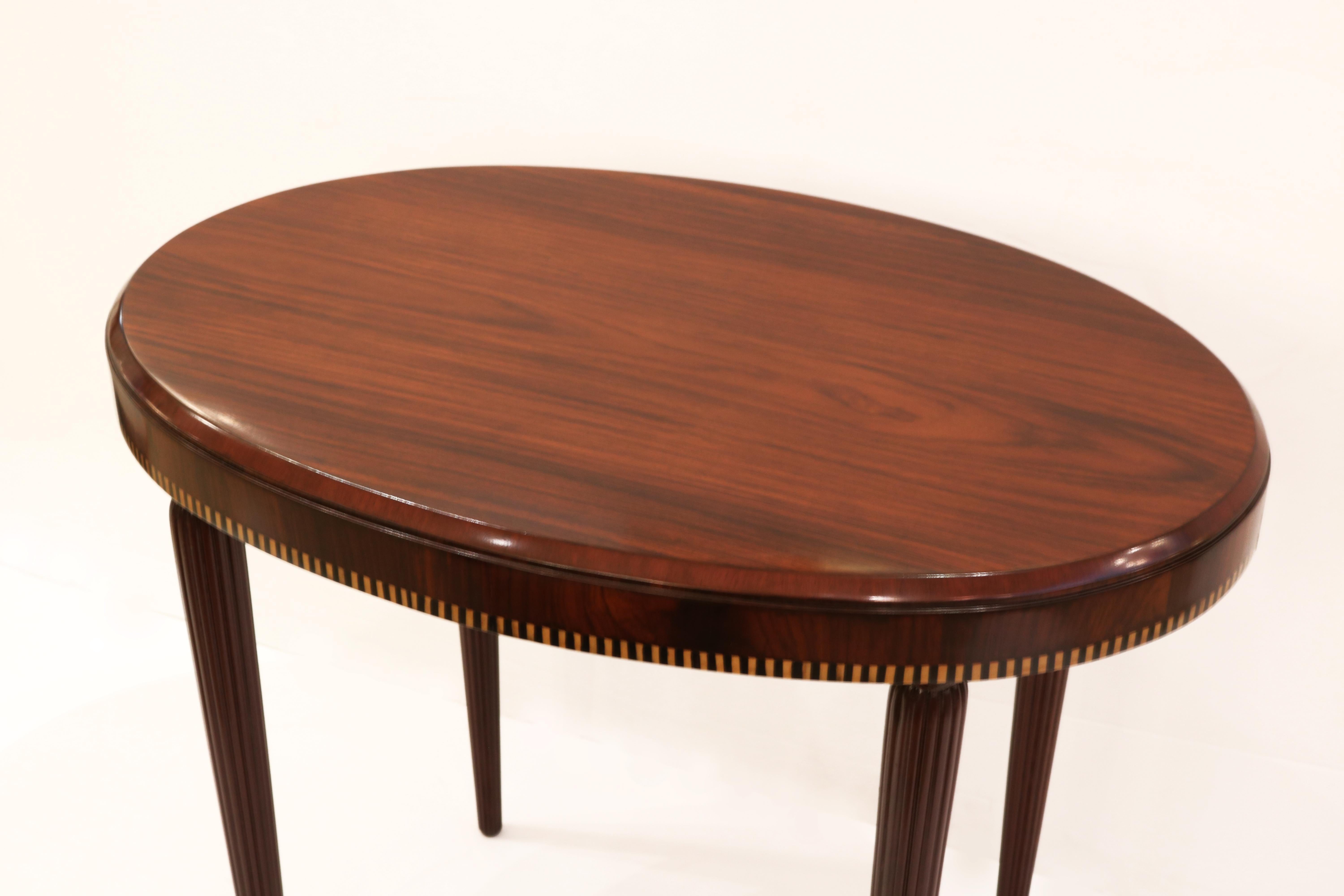 Table de lampe ovale Art Déco avec des pieds cannelés effilés,
Des incrustations de bois fruitier et d'ébène entourent le tablier.