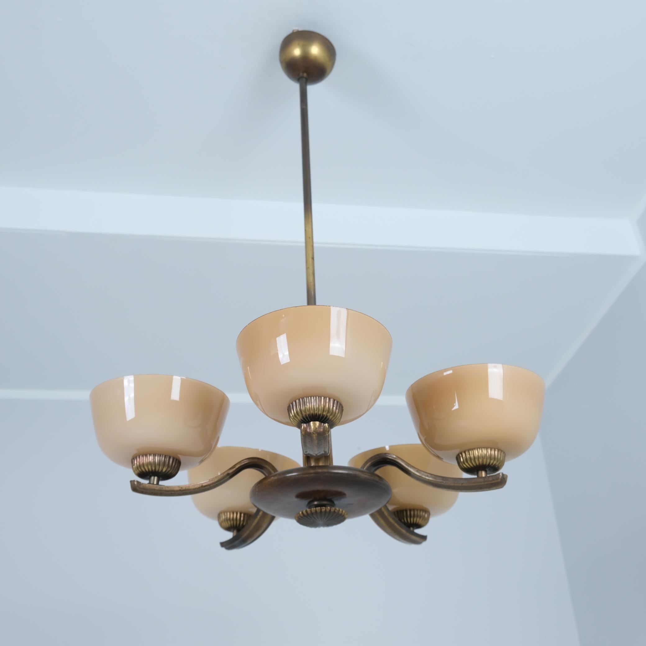A beautiful example of Paavo Tynell 1930s early lamps. A marvelous piece with dark stained birch, polished and oxidized brass with blown glass shades. The lamp is in its original condition. The blown glass shades are light beige with a hint of