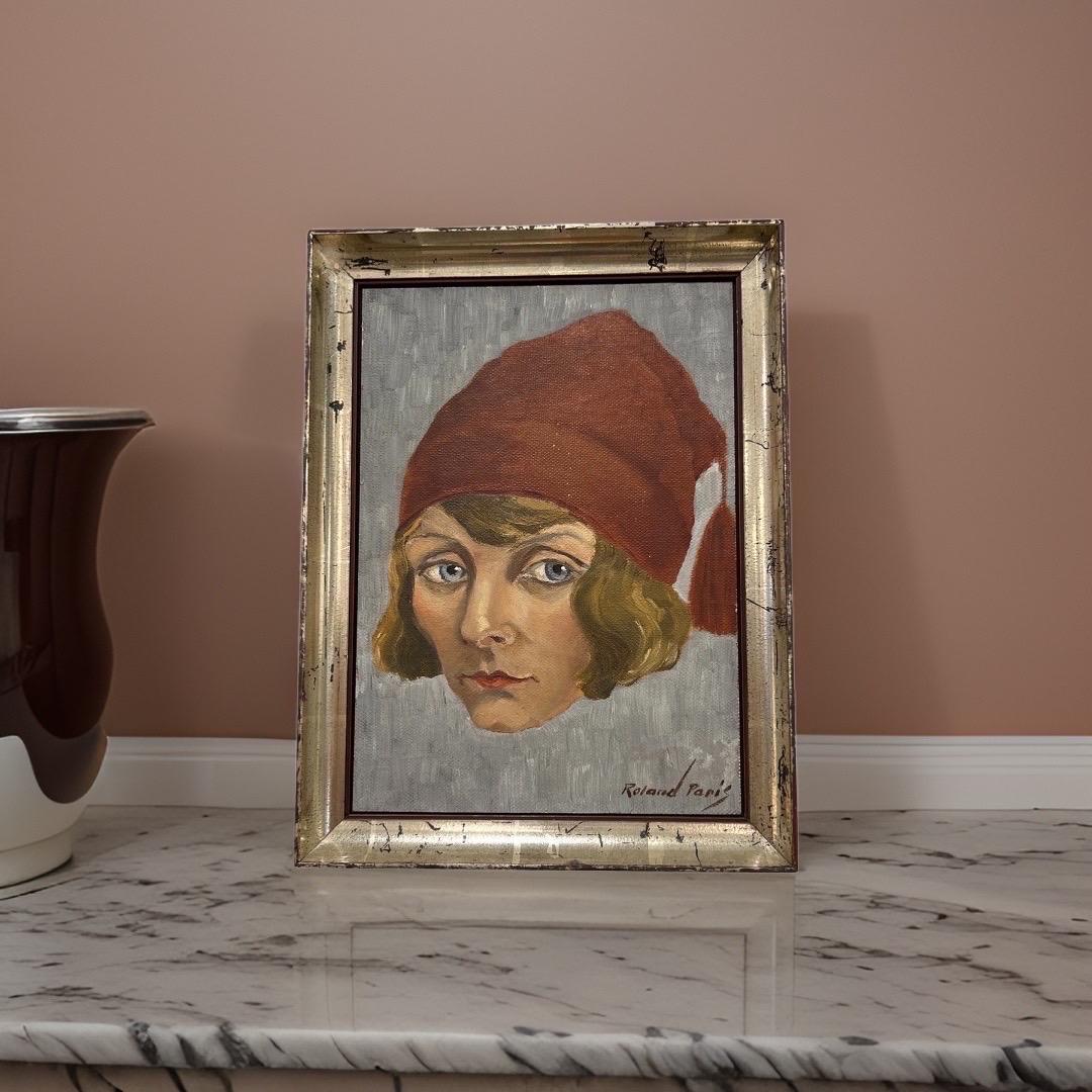 Oil on Canvas painting depicting a Blue Eyed Woman with a Red beanie hat. 

Signature: Roland Paris