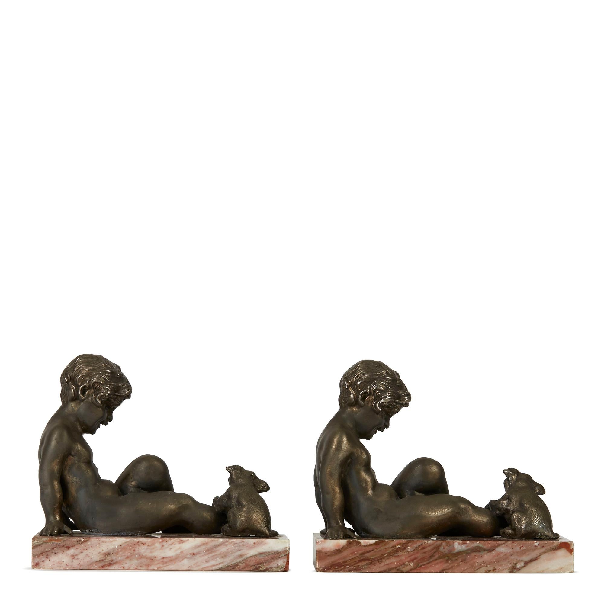 A stylish pair of Art Deco figural bookends with a bronzed metal figure of a seated boy with a puppy licking his toes. The figures are mounted on rectangular red veined marble bases and are not marked.
Probably French, not marked.
 