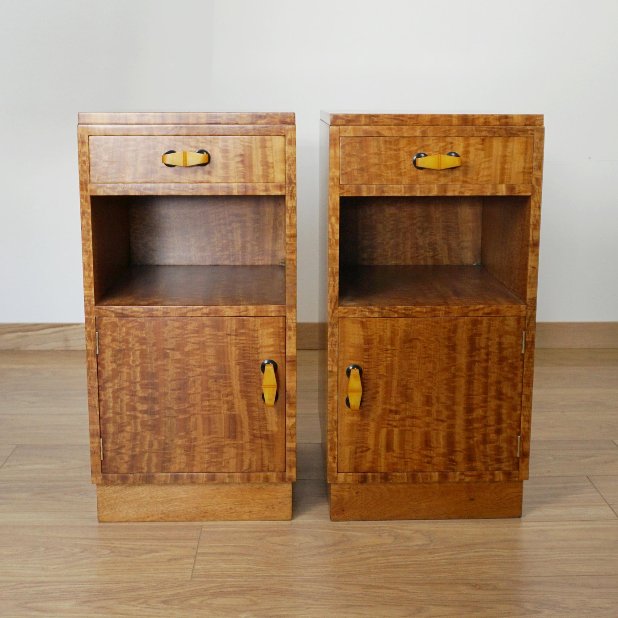 An Art Deco pair of Bedside Cabinets. Satinwood veneered with original bakelite handles. 

