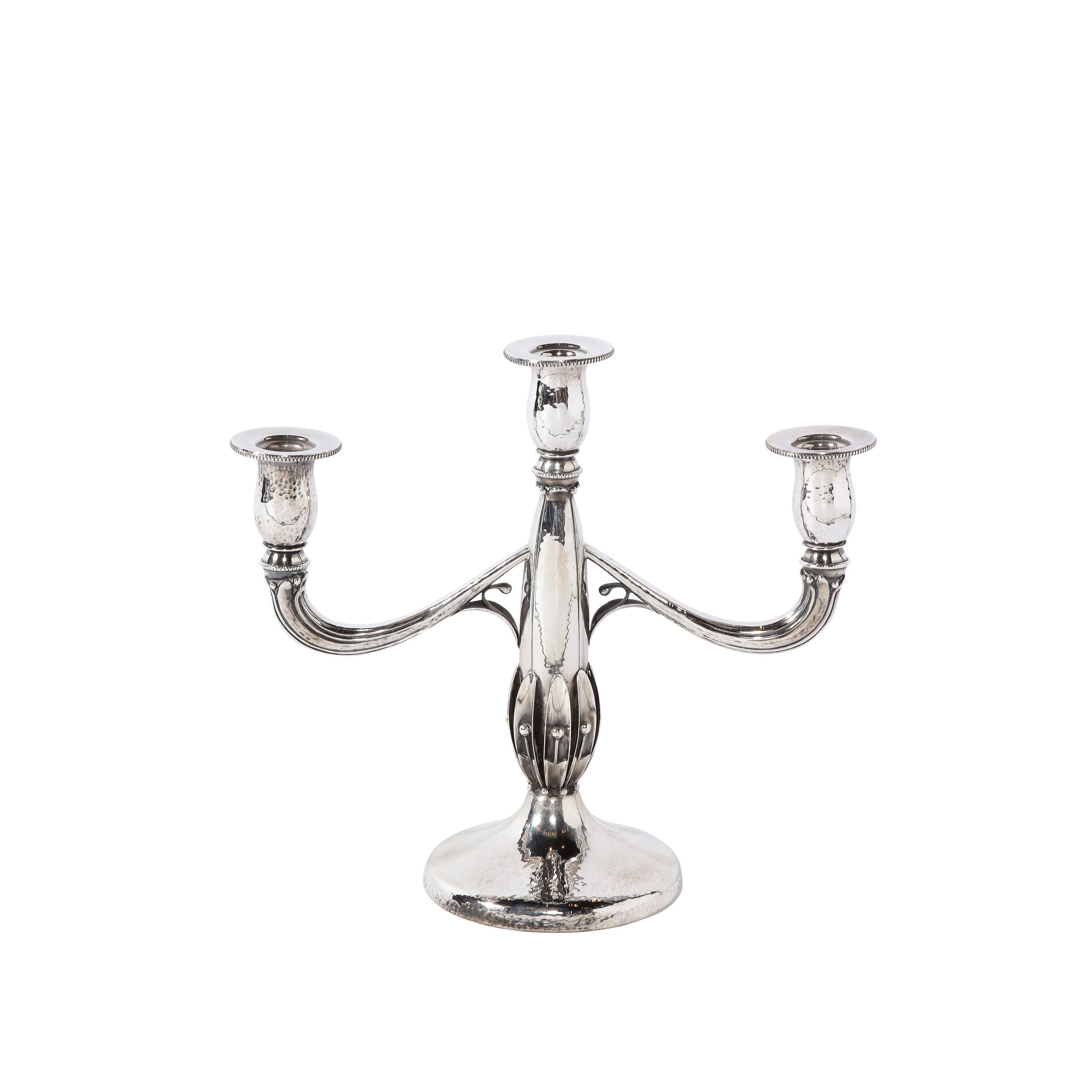 This exquisite pair of Art Deco sterling silver candelabras was realized in the United States circa 1930. They feature convex circular hand hammered bases with a dappled texture that ascend into a subtly conical bodies. The protuberant base of the
