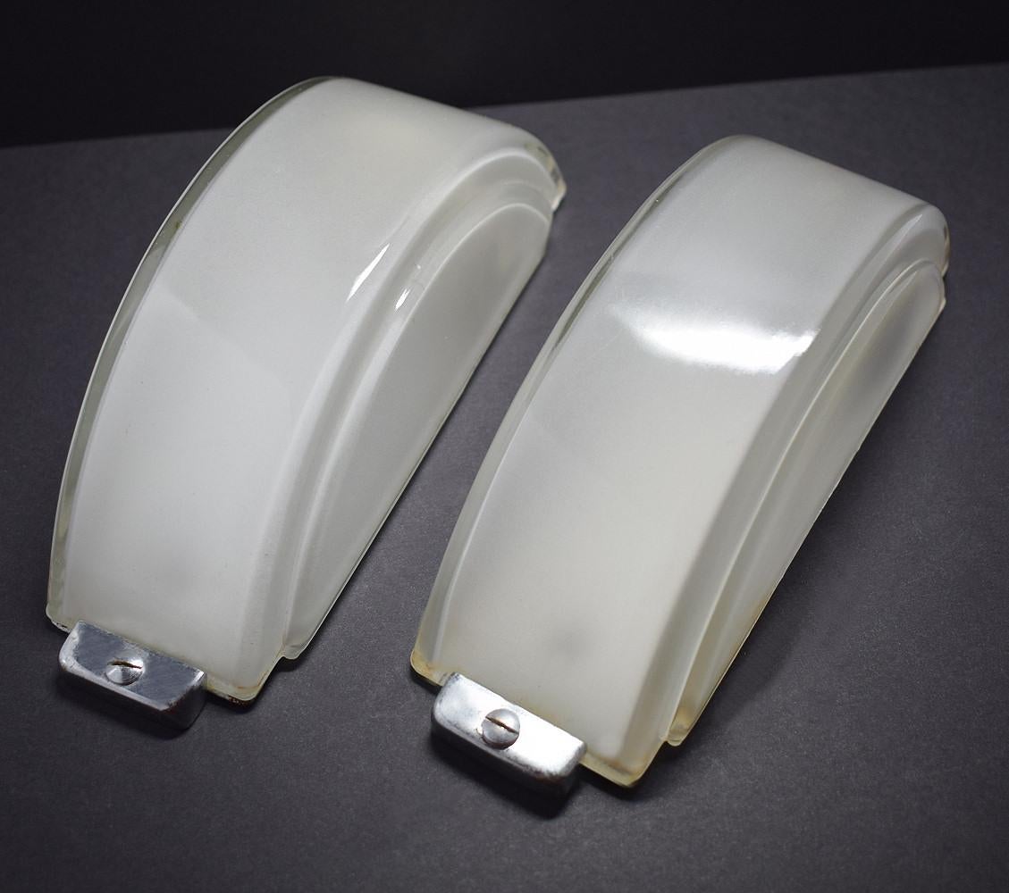 A golden opportunity to buy a wonderful pair of original 1930s Art Deco wall lights originating from England. Crescent in shape and slightly stepped with a chrome back plate and surround which holds the opaque glass shades. The glass as a slight